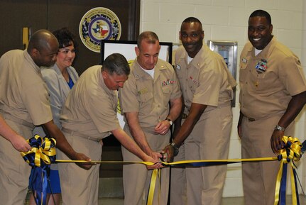 Joined by fellow Navy leadership, Rear Adm. William Roberts, commandant, Medical, Education and Training Campus, cuts the ribbon during a June 25 ceremony officially opening the Wounded, Ill & Injured Annex at the Navy Operational Support Center, Joint Base San Antonio-Fort Sam Houston. The Annex will serve as an administrative liaison for Navy, Marine Corps and Coast Guard members receiving treatment through the San Antonio Military Medical Center at JBSH-FSH. Annex staff will also provide support to service members' families and a better means of communication, patient advocacy and navigation through complex medical issues while service members receive treatment. The Annex is a detachment of the Naval Health Clinic Corpus Christi.