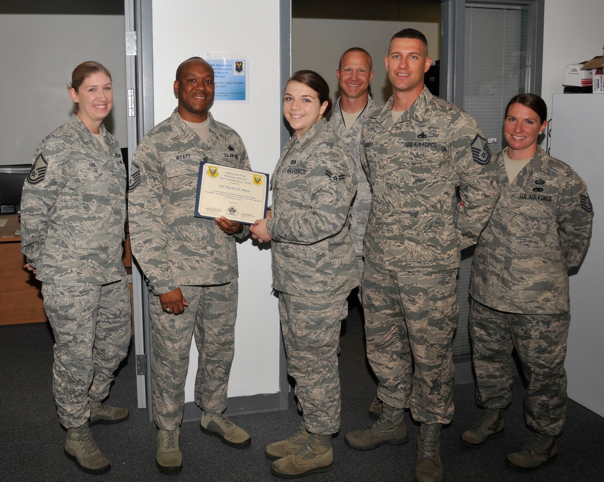 Members of Whiteman’s Top III present Airman 1st Class Kaytlyn Bulen, 509th Operations Support Squadron aviation resource manager, with the Top 3 MVP Award, June 25, 2013, at Whiteman Air Force Base, Mo. Bulen manages flight records for all Whiteman aviators and provides assistance for exercises such as the recent Consolidated Unit Inspection. (U.S. Air Force photo by Airman 1st Class Keenan Berry/Released)