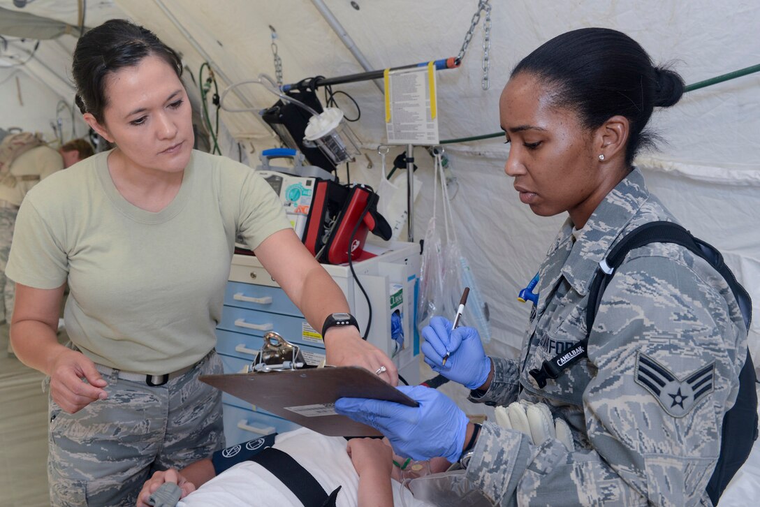 U.S. Air National Guard Capt. Rose Adams, clinical nurse, 136th Medical Group, and Senior Airman Tameko Brigham, medical technician, 301st Medical Squadron, diagnoses a mock casualty while participating in a mass casualty exercise at Naval Air Station Fort Worth, Joint Reserve Base, Texas, June 23, 2013. The two units combine efforts to fulfill their annual training requirements. (Air National Guard photo by Master Sgt. Charles Hatton/released)