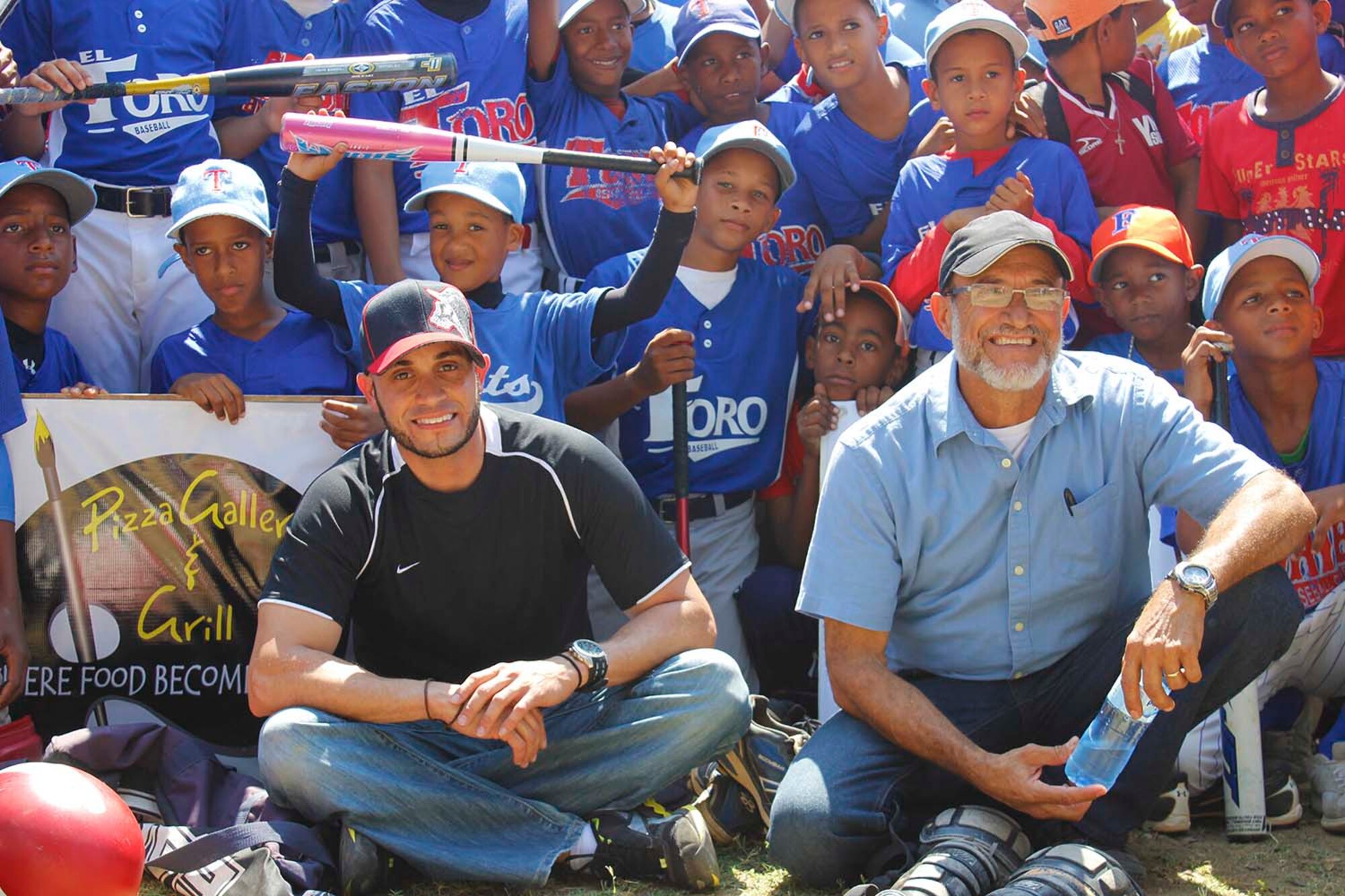 130626-F-ZZ999-019 – Rafael Nuñez Jr. (left) and Rafael Nuñez Sr. (right) pose with a group of boys from Villa Gonzalez, Dominican Republic, after distributing more than 2,000 pieces of baseball equipment.  Nuñez Jr., a computer security manager with the Air Force Technical Applications Center at Patrick AFB, Fla., traveled with 26 donors and supporters to the island nation in early June 2013.  Because of an outpouring of support and contributions, Nuñez founded a non-profit organization called ‘Giving Feels Awesome,’ whose charter is to “embrace opportunities to connect givers at every level to underprivileged children in need of a lift, hope and happiness through sports participation.” (Courtesy Photo)