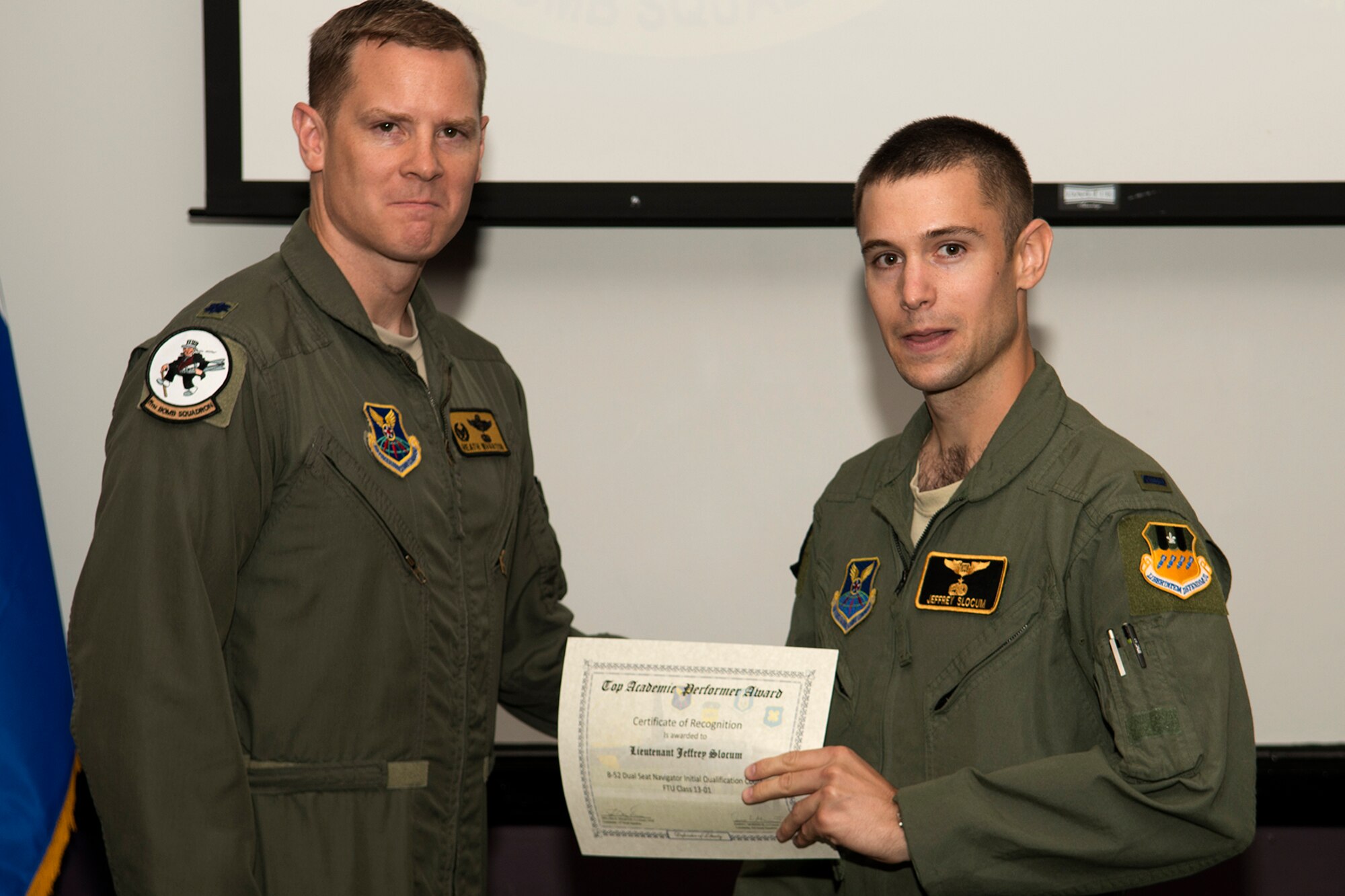 U.S. Air Force Lt. Col. William Wharton, 11th Bomb Squadron commander, presents the Dual Seat Navigator Outstanding Academic Performer certificate to 1st Lt. Jeffrey Slocum, during a Formal Training Unit graduation ceremony, June 14, 2013, Barksdale Air Force Base, La. Slocum achieved an overall academic average of 99.75 percent and was also the Dual Seat Navigator Distinguished Graduate. (U.S. Air Force photo by Master Sgt. Greg Steele/Released)