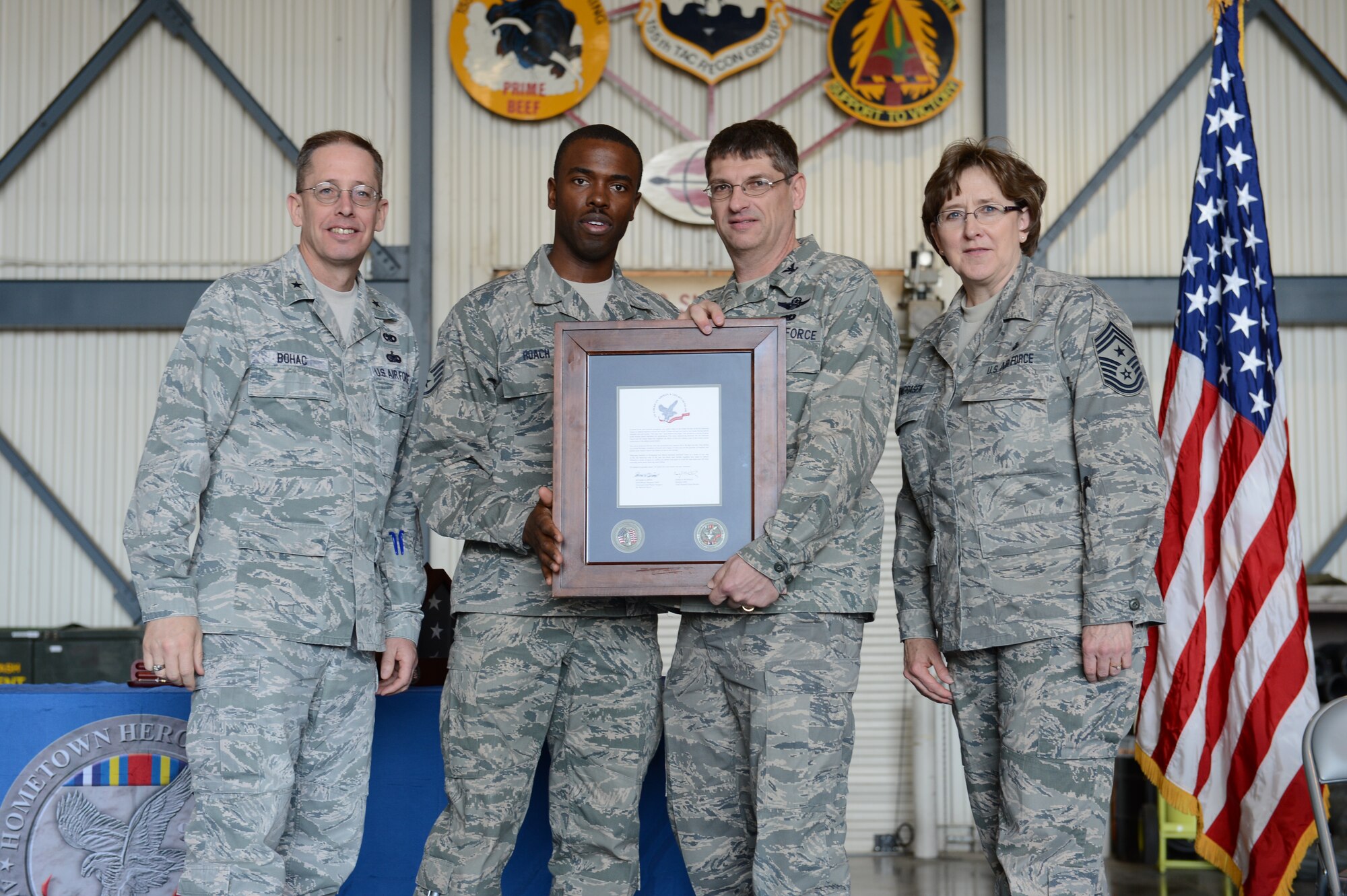 Brig. Gen. Daryl Bohac, Nebraska National Guard's assistant adjutant general-Air, along with Col. Keith Schell, commander of the 155th Air Refueling Wing and Chief Nancy Vondrasek, the 155th ARW Command Chief award Staff Sgt. Jarrell Roach, a civil engineer structural maintainer, at the Hometown Heroes Salute Ceremony, April 6, 2013, at the Nebraska National Guard air base in Lincoln, Neb. The ceremony is used to honor the family members, friends and deployed unit members who sacrificed so much for freedom during a deployment. (U.S. Air National Guard Photo by Staff Sgt. James Lieth/released)