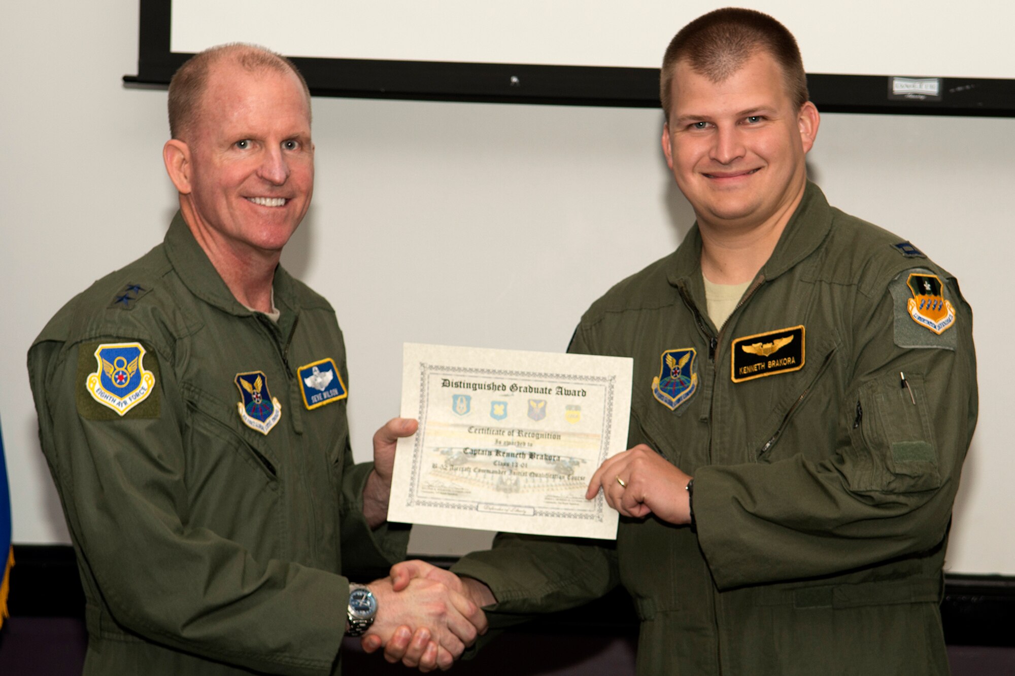 U.S. Air Force Maj. Gen. Stephen Wilson, Eighth Air Force commander, presents the Aircraft Commander Distinguished Graduate certificate to Capt. Kenneth Brakora, during a Formal Training Unit graduation ceremony, June 14, 2013, Barksdale Air Force Base, La. The award is a culmination of academic tests, flight evaluations, officership, attitude and professional bearing that was consistently and clearly above their peers. (U.S. Air Force photo by Master Sgt. Greg Steele/Released)