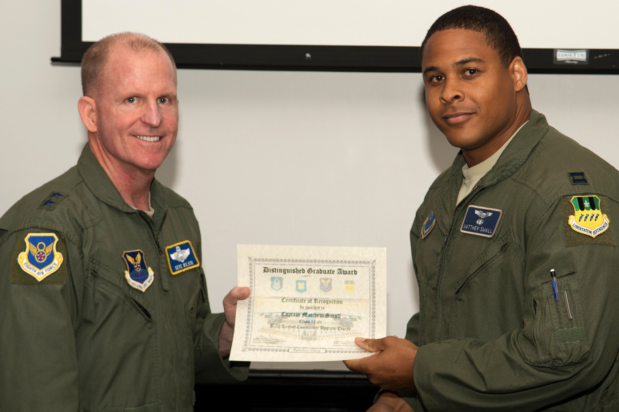 U.S. Air Force Maj. Gen. Stephen Wilson, Eighth Air Force commander, presents the Pilot Upgrade Distinguished Graduate certificate to Capt. Matthew Small, during a Formal Training Unit graduation ceremony, June 14, 2013, Barksdale Air Force Base, La. The award is a culmination of academic tests, flight evaluations, officership, attitude and professional bearing that was consistently and clearly above their peers. (U.S. Air Force photo by Master Sgt. Greg Steele/Released)