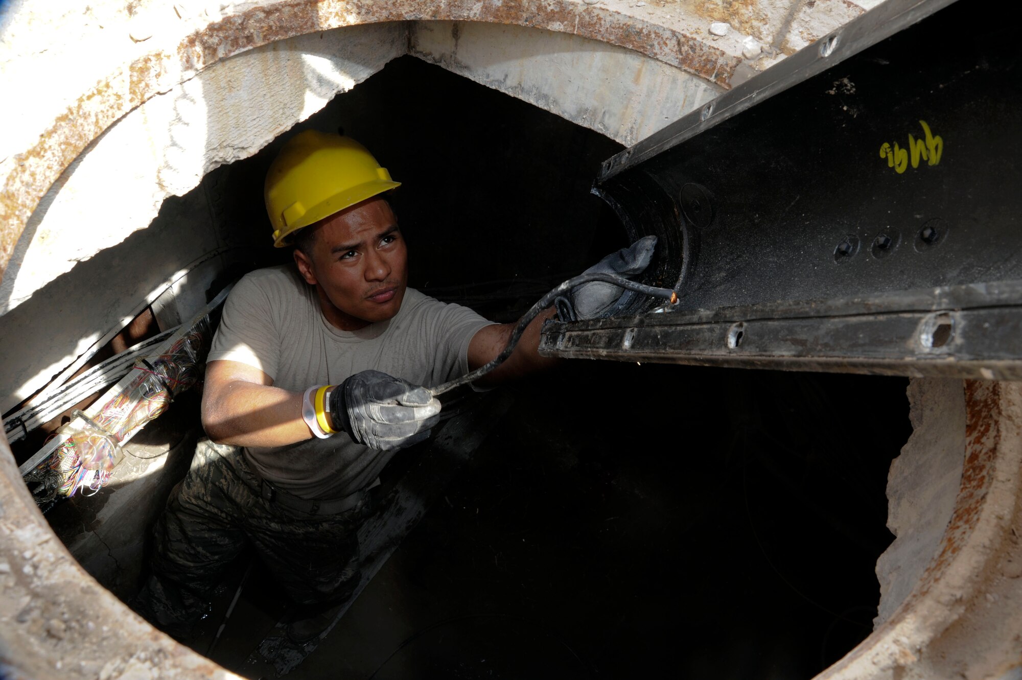 Senior Airman Joshua Cruz removes a splice case to check the telephone and alarm cables inside a manhole at the 379th Air Expeditionary Wing in Southwest Asia, June 27, 2013. The 379th Expeditionary Communications Squadron Cables Maintenance and Antenna Systems technicians work closely with the Communications Focal Point to resolve communication issues affecting the 379th AEW. Cruz is a 379th ECS CMAS technician deployed from Yokota Air Base, Japan. (U.S. Air Force photo/Senior Airman Bahja J. Jones.) 