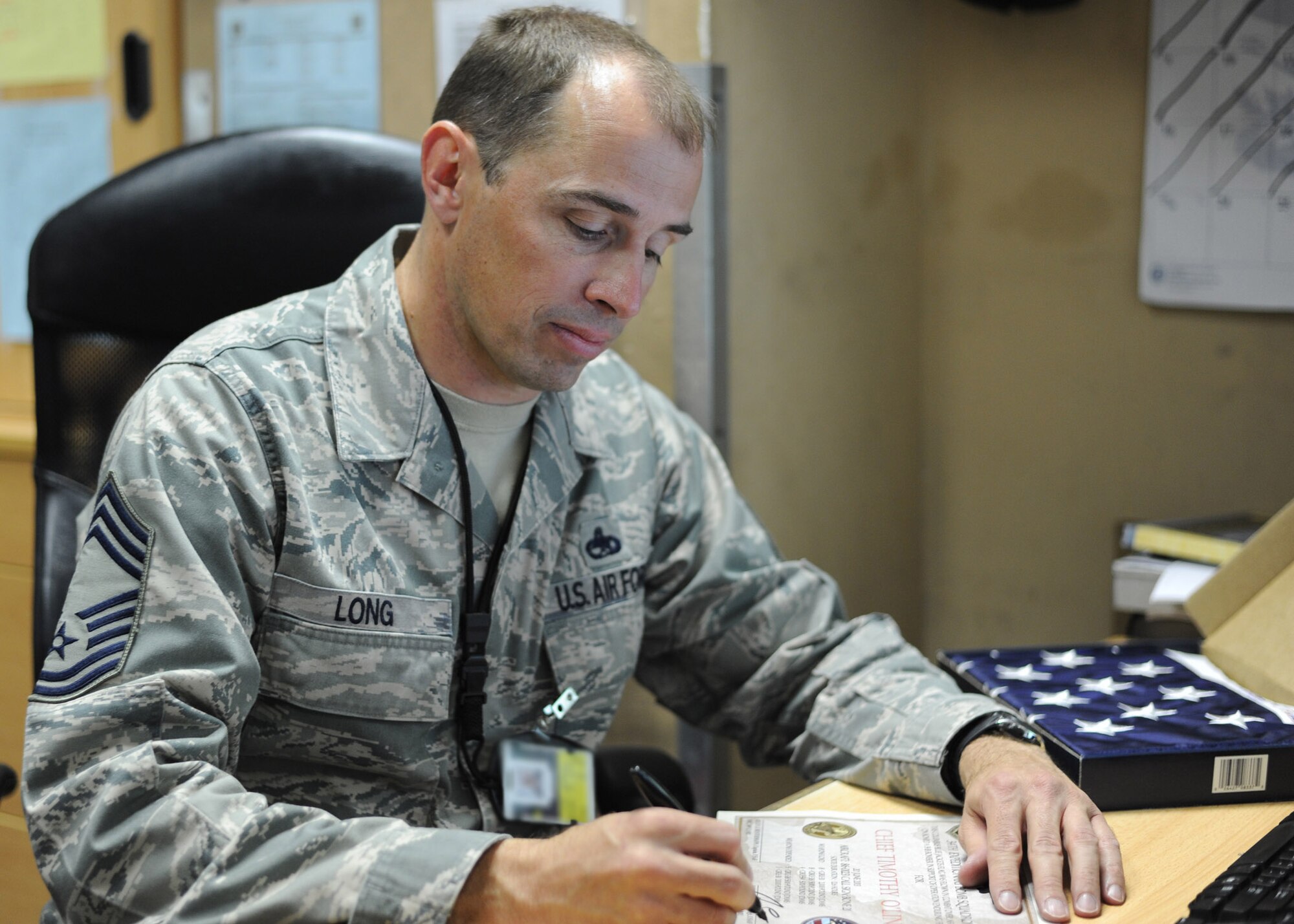 Chief Master Sgt. James Long signs a certificate to be included with a flag flown in a B-1B Lancer at the 379th Air Expeditionary Wing in Southwest Asia, June 21, 2013. Long is the 34th Expeditionary Aircraft Maintenance Unit superintendent deployed from Ellsworth Air Force Base, S.D. (U.S. Air Force photo/Senior Airman Bahja J. Jones) 