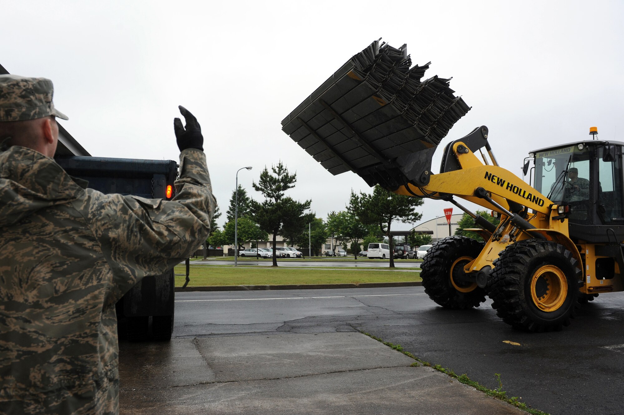 U.S. Air Force Senior Airman Travis Stout signals to Senior Airman Ivan Abreu to move the forklift closer to a dump truck at Misawa Air Base, Japan, June 27, 2013. Stout and Abreu are both structural journeymen from the 35th Civil Engineer Squadron. (U.S. Air Force photo by Airman 1st Class Kia Atkins)