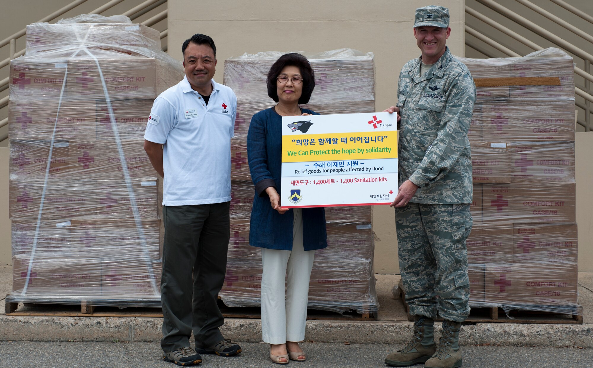 Colonel S. Clinton Hinote, 8th Fighter Wing commander, presents donated supplies with Akinori Tsuchida, American Red Cross representative, left, to Yi Hui-eun, Korean Red Cross director of staff, at Kunsan Air Base, Republic of Korea, June 17, 2013. The Wolf Pack supported the transfer of more than 1,400 comfort kits to the Korean Red Cross. (U.S. Air Force photo by Senior Airman Armando A. Schwier-Morales)
