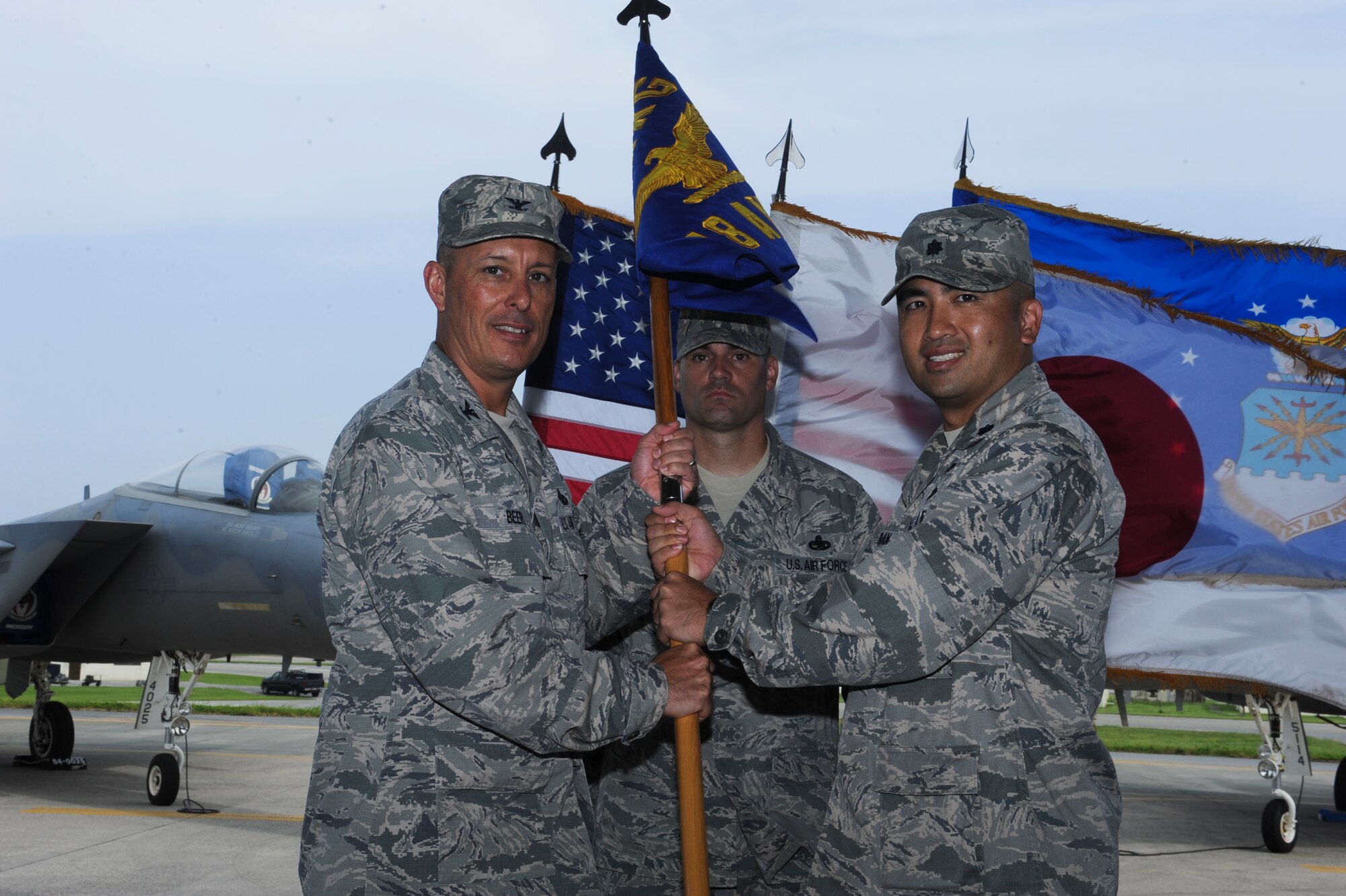 U.S. Air Force Lt. Col. John Tran, 18th Aircraft Maintenance Squadron commander, accepts the guidon from Col. Brian Beers, 18th Maintenance Group commander, during a change of command ceremony on Kadena Air Base, Japan, June 27, 2013. Tran now commands the 18th AMXS, whose primary responsibilities are the maintenance, generation and mobilization of more than 50 F-15 Eagle aircraft, the only F-15s in the Asian and Western Pacific region.  (U.S. Air Force photo by Airman 1st Class Justin Veazie/Released)