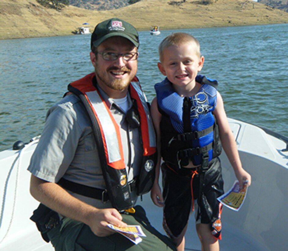 Park ranger Brady Wendt presents a young boater with a "You've Been Caught Being Good" ice cream voucher for wearing his life jacket while enjoying the water at Lake Kaweah, the U.S. Army Corps of Engineers Sacramento District park near Lemon Cove, Calif. (U.S. Army photo by Bill Spring / Released)