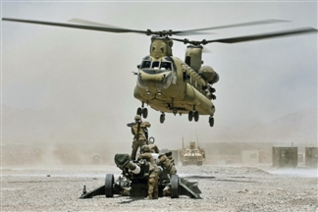 U.S. Army soldiers wait as a CH-47 Chinook helicopter approaches them for a hook up of an M777A2 howitzer at Forward Operating Base Hadrian in Afghanistan on June 18, 2013.  The howitzer will be airlifted from Hadrian to Kandahar Airfield.  The Chinook is attached to Task Force Knighthawk, 2-10 Aviation Regiment.  