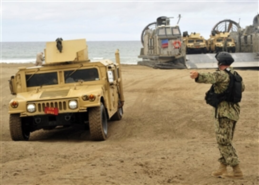 U.S. Navy Petty Officer 3rd Class Bryan Dingess directs the driver of a Humvee as it hits the beach during exercise Dawn Blitz at Camp Pendleton, Calif., on June 24, 2013.  Coalition forces from the U.S., Canada, New Zealand and Japan participated in the multilateral amphibious exercise that is designed to strengthen international partnerships.  Dingess is a Navy boatswain’s mate attached to Beach Master Unit 1.  