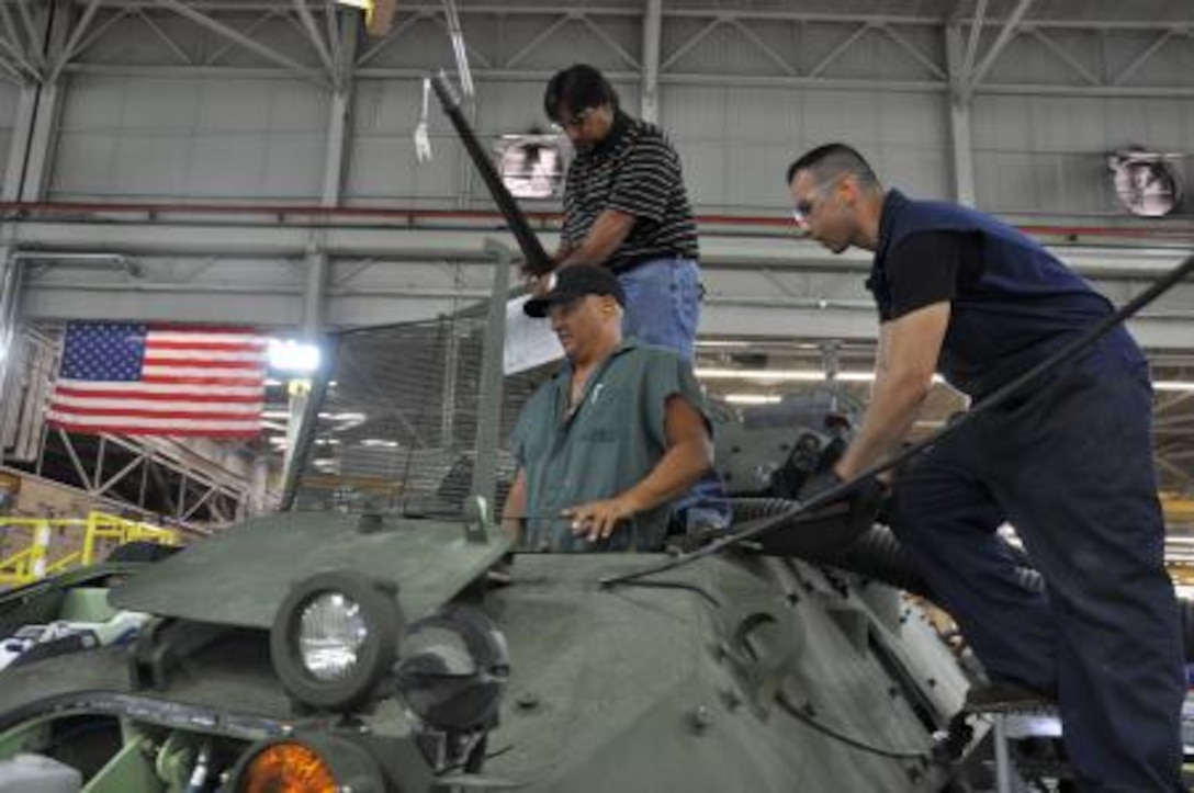 Kenny Phillips, (top) the branch head of quality control on PPB, MDMC, meticulously inspects the work that Adolpho Madero, (bottom left) and Chris Mendez, (right) heavy equipment mobile mechanics on MCLB Barstow, have done on a light armored vehicle, June 25. Phillips inspects a variety of military vehicles and gear to ensure their quality.


