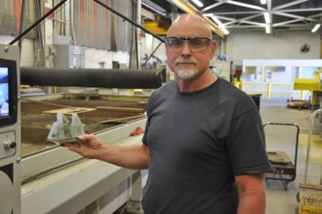 Doug Martin, a water jet operator on Marine Corps Logistics Base Barstow, shows a sailboat designed using excess bullet-proof glass, June 17. The boat was made in a creative way to test out the settings of the machine, and also to showcase the precision of the water jets.


