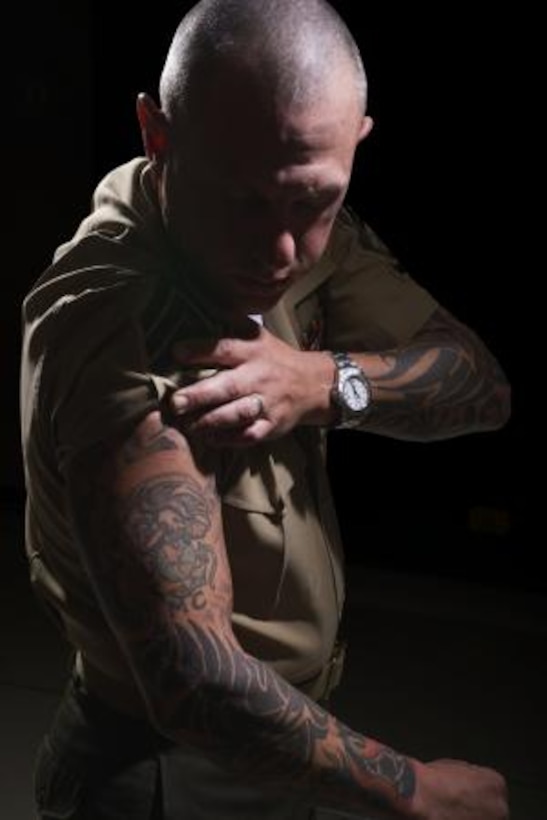 Gunnery Sergeant Dustin Hamilton, a safety specialist on Marine Corps Logistics Base Barstow, rolls his sleeve up June 21, to show a motivational tattoo on his arm. Marines often get tattoos as a sign of pride for their service. (Photo by Carlos Guerra)


