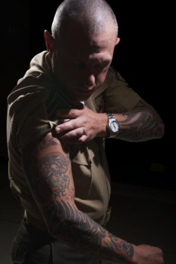 Gunnery Sergeant Dustin Hamilton, a safety specialist on Marine Corps Logistics Base Barstow, rolls his sleeve up June 21, to show a motivational tattoo on his arm. Marines often get tattoos as a sign of pride for their service. (Photo by Carlos Guerra)


