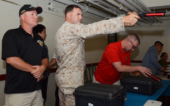 John Schwent (left), head coach of the Marine Corps Wounded Warrior Shooting Team, observes as Gunnery Sgt. Curt Collins, operations chief, Wounded Warrior Battalion West — Detachment Hawaii, and Chief Warrant Officer 3 Ryan Eckroth, a wounded warrior with the detachment, practice shooting a compressed-air pellet pistol in the Kona Room of the Officers’ Club, June 25, 2013. (U.S. Marine Corps photo by Kristen Wong)