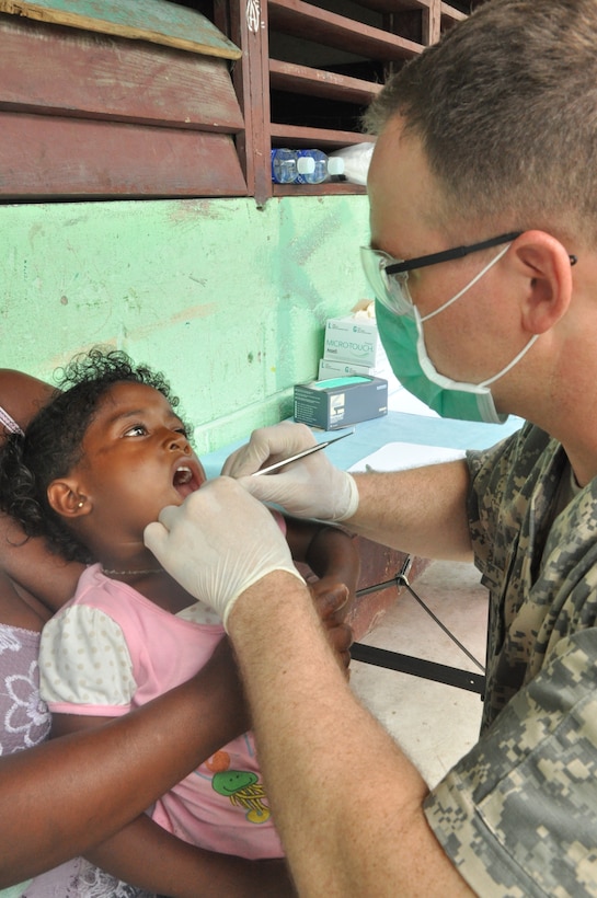 U.S. Army Maj. (Doctor) Jeff Wolfe, Joint Task Force-Bravo Medical Element dentist officer-in-charge, examines a child’s teeth during a medical readiness training exercise held in the remote region of Bara Patuca, Gracias a Dios, June 25-26, 2013. During the two-day exercise the make shift dental clinic visited with more than 170 patients and extracted more than 80 teeth. 

