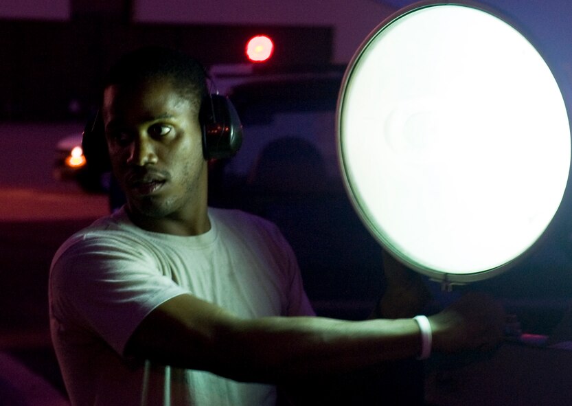 U.S. Air Force Senior Airman Joshua Jones, 7th Equipment Maintenance Squadron, adjusts a flood light June 26, 2013, at Dyess Air Force Base, Texas. First sergeants began preparations shortly before 9 p.m. and grilled until after midnight. (U.S. Air Force photo by Airman 1st Class Peter Thompson/Released)