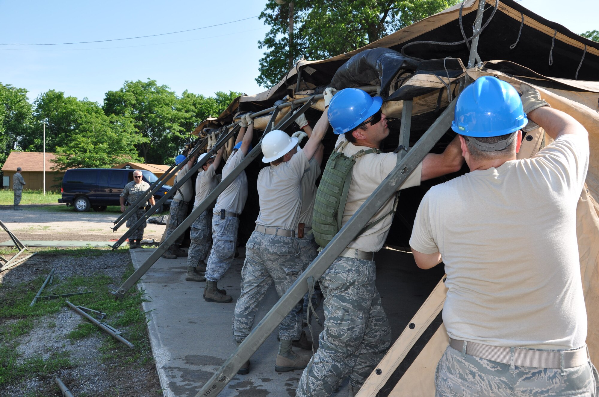 Members of the 442nd Civil Engineer Squadron work together to lift the side of a temper tent during field training here, June 20, 2013. During the field training, members of 442nd CES set up and inventoried tents, prepared and manned defensive fighting positions. The 442nd CES is part of the 442nd Fighter Wing, an A-10 Thunderbolt II Air Force Reserve unit at Whiteman Air Force Base, Mo. (U.S. Air Force photo by Senior Airman Wesley Wright/ Released)
