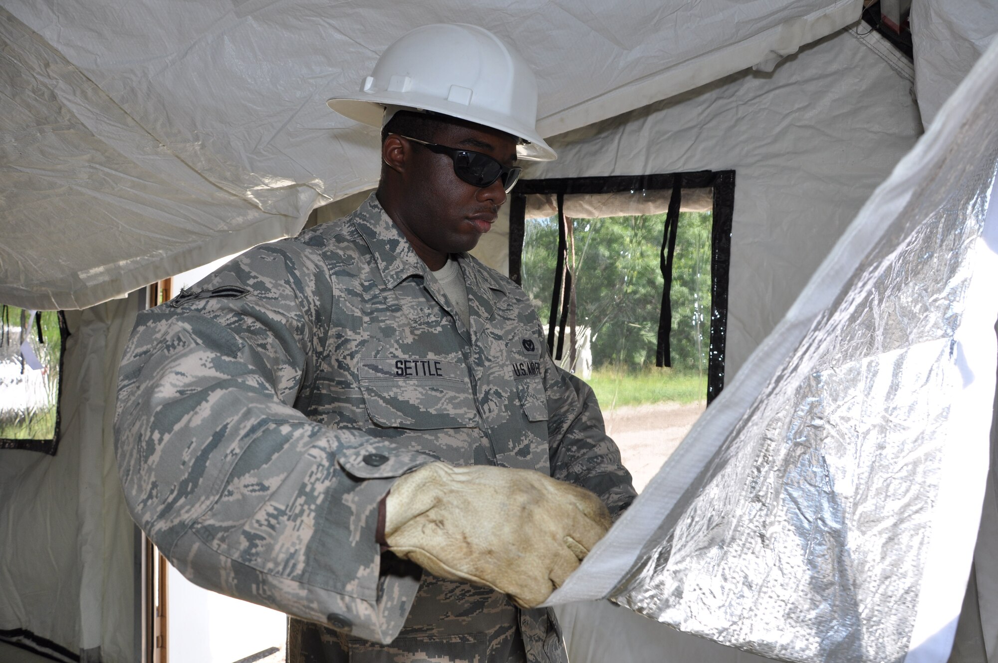 Airman 1st Class Kelvin Settle, 442nd Civil Engineer Squadron structures technician, rolls up the windows during the setup of a small shelter system tent here, June 20, 2013. During the field training, members of 442nd CES set up and inventoried tents, prepared and manned defensive fighting positions. The 442nd CES is part of the 442nd Fighter Wing, an A-10 Thunderbolt II Air Force Reserve unit at Whiteman Air Force Base, Mo. (U.S. Air Force photo by Senior Airman Wesley Wright/ Released)