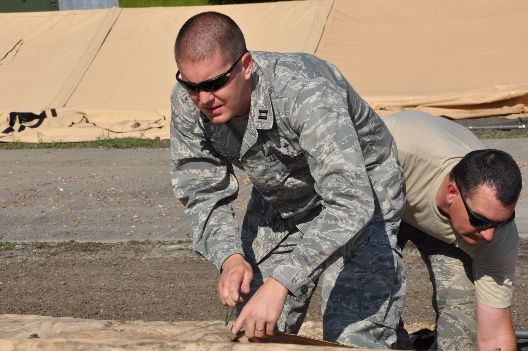Capt. Edward Sanders IV, 442nd Fighter Wing chaplain, helps tie down temper- tent components during field training here, June 20, 2013. The chaplain team was on-scene to lend support, and a helping hand, during the 442nd CES annual tour training. During the field training, members of 442nd CES set up and inventoried tents, prepared and manned defensive fighting positions. The 442nd CES is part of the 442nd Fighter Wing, an A-10 Thunderbolt II Air Force Reserve unit at Whiteman Air Force Base, Mo. (U.S. Air Force photo by Senior Airman Wesley Wright/ Released)