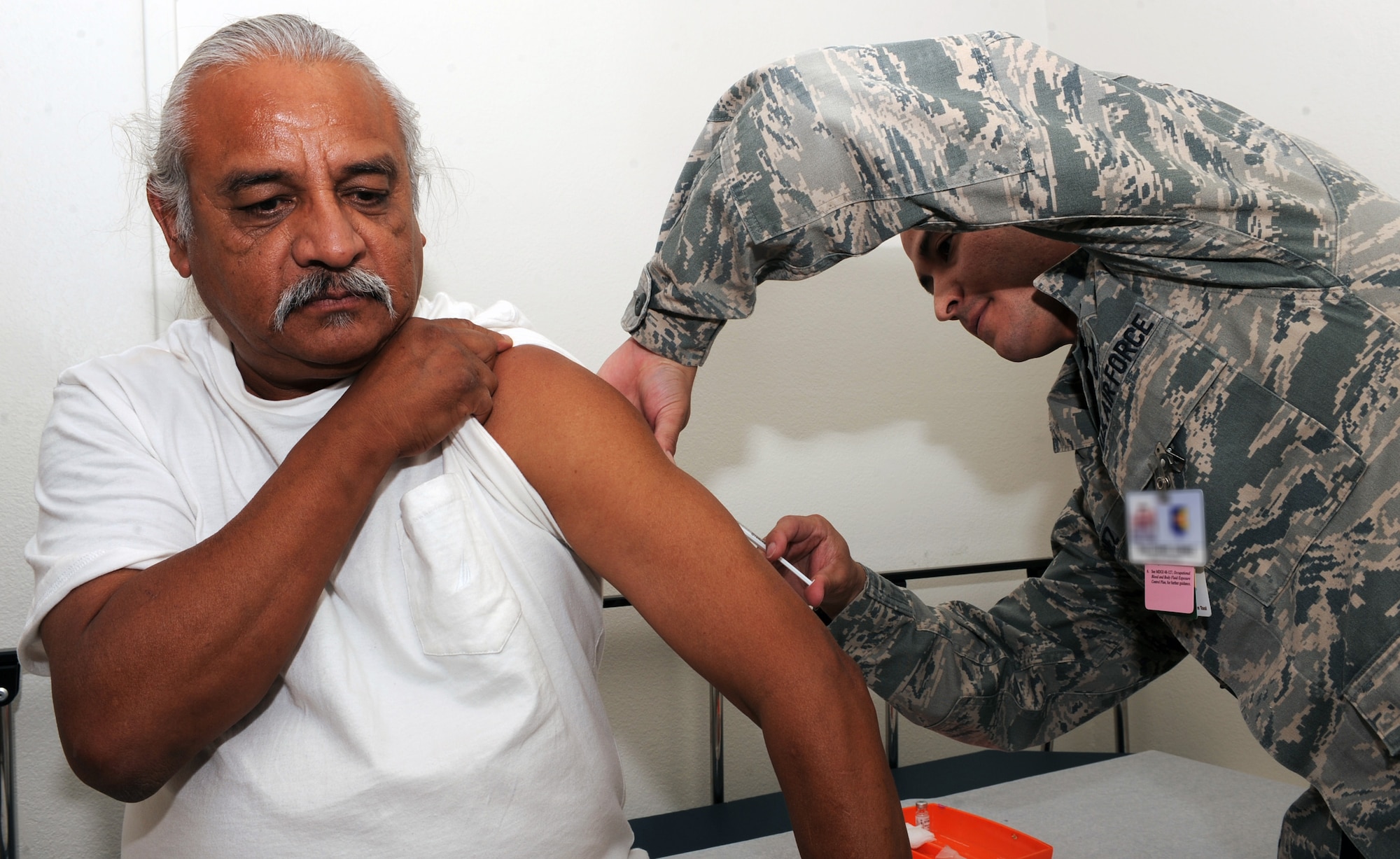 U.S. Air Force Tech. Sgt. Daniel Gomez, 355th Medical Operations Squadron aerospace medicine technician, gives a patient a vaccine shot at the immunizations clinic at Davis-Monthan Air Force Base, Ariz., June 27, 2013. The355th MDOS provides medical care to maximize the health and welfare of our current and retired warriors and their family members, both in theater and at home. (U.S. Air Force photo by Senior Airman Christine Griffiths/Released) 