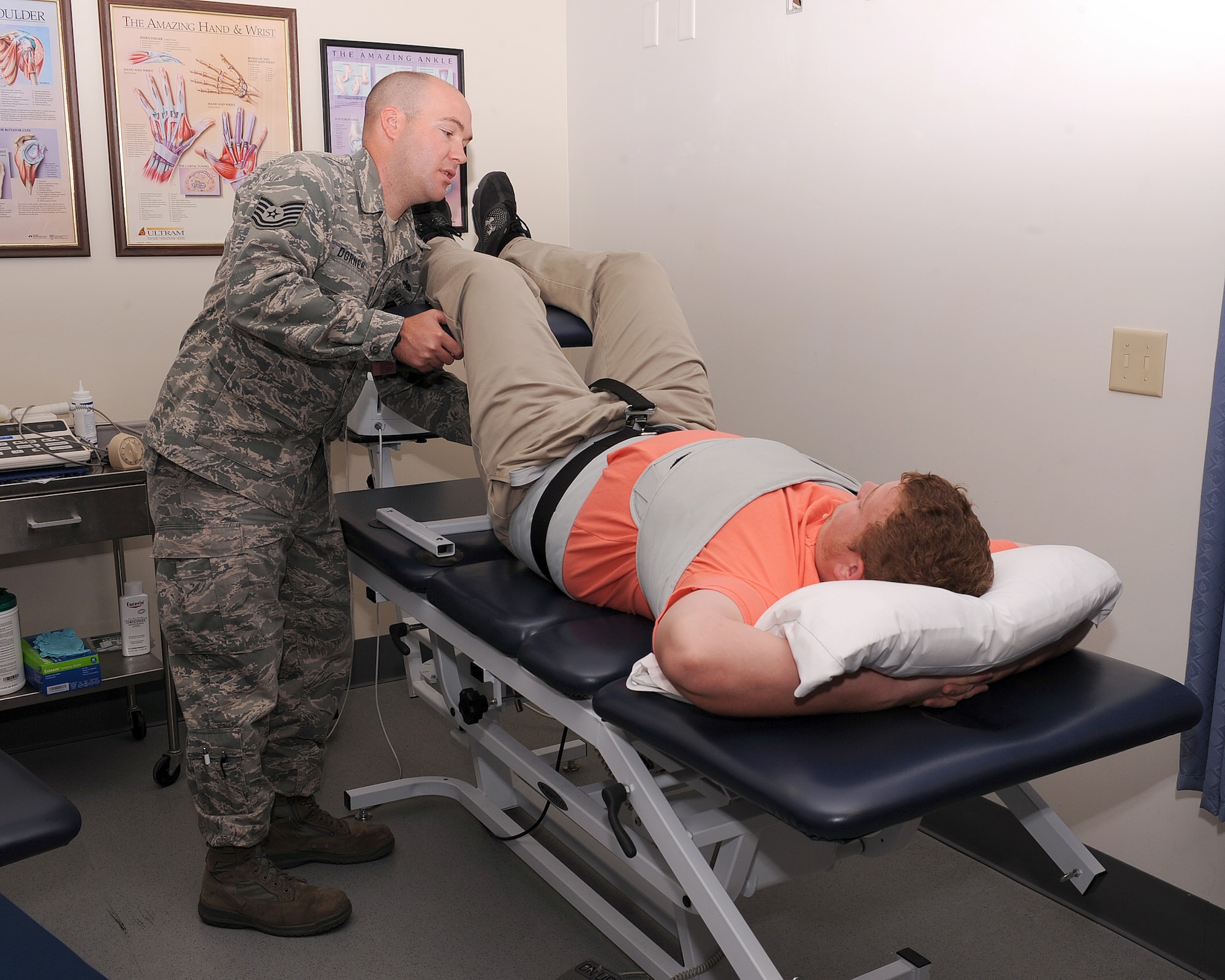 U.S. Air Force Tech. Sgt. Gregory Dorner, 355th Medical Operations Squadron physical therapist, situates a patient on the traction machine at the physical theraphy clinic at Davis-Monthan Air Force Base, Ariz., June 27, 2013. The traction machine is used to create a space between the vertebrae and stretch the back to relieve any pain on the patient.  (U.S. Air Force photo by Senior Airman Christine Griffiths/Released) 