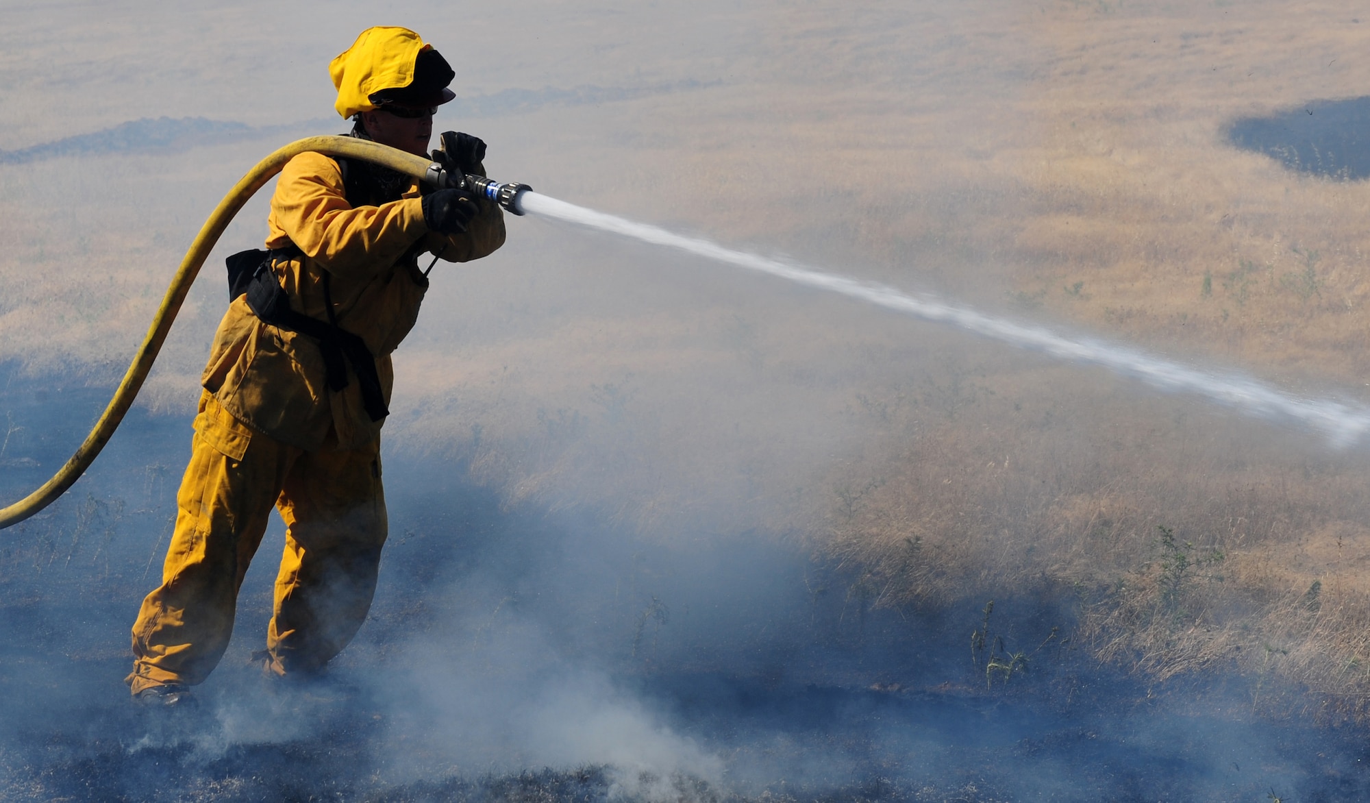 Staff Sgt. Brandon Albrecht, 9th Civil Engineering Squadron firefighter, repels flames at the M-60 firing range on Beale Air Force Base, Calif., June 27, 2013. The Beale fire department worked with local fire departments to extinguish a prescribed burn. (U.S. Air Force photo by Airman 1st Class Bobby Cummings/Released)