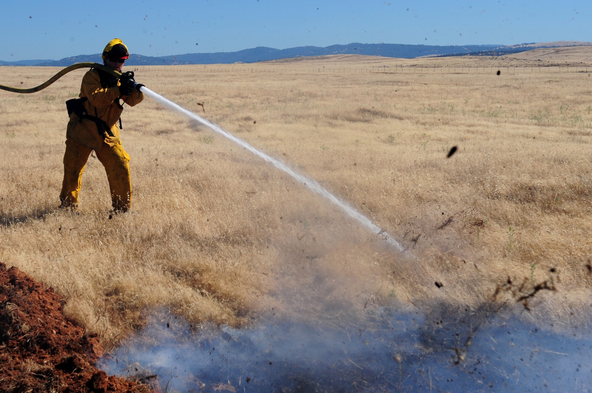Staff Sgt. Kyle Dobler, 9th Civil Engineering Squadron firefighter, extinguishes a flame at the M-60 range during a prescribed burn on Beale Air Force Base Calif., June 27, 2013. Brush fires on Beale occur often during the summer months. (U.S. Air Force photo by Airman 1st Class Bobby Cummings/Released)