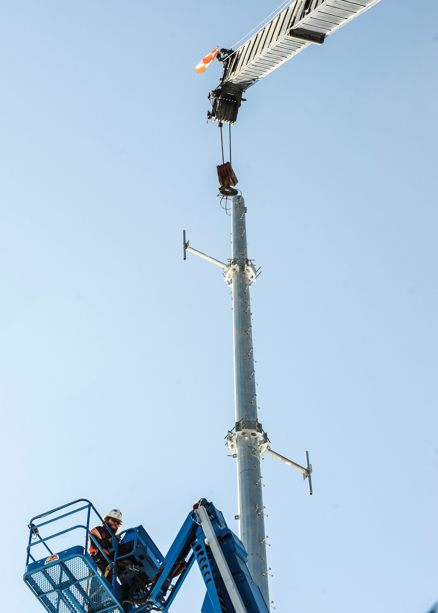 A DWG and Associates contractor goes 100 feet in the air to undo a hook from the 460th Space Communication Squadron newest communication mono pole June 21, 2013, on Buckley Air Force Base, Colo. The pole will be able to transmit and receive signals five times further than previously done. (U.S. Air Force photo by Staff Sgt. Christopher Gross/Released)