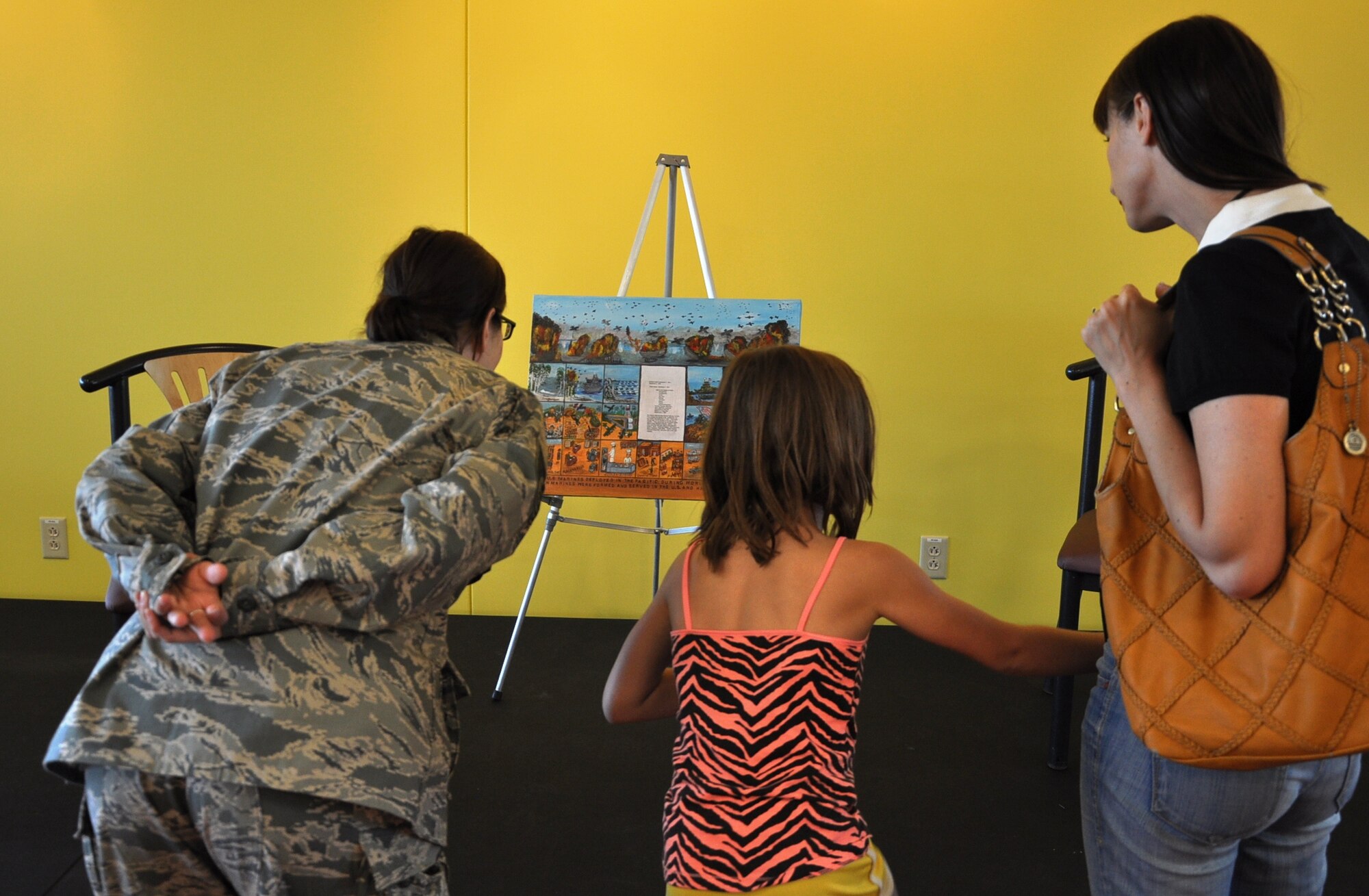 Women who attended the Women’s Empowerment Group gathering view the painting of Marge Alexander, member of the Marine Corps Women’s Reserve during World War II, June 26, 2013, at the Panther Den on Buckley Air Force Base, Colo. At the event, Alexander unveiled the painting, which depicts various battles of World War II as well as the roles of women in the Women’s Reserve. (U.S. Air Force photo by Staff Sgt. Kali L. Gradishar/Released)