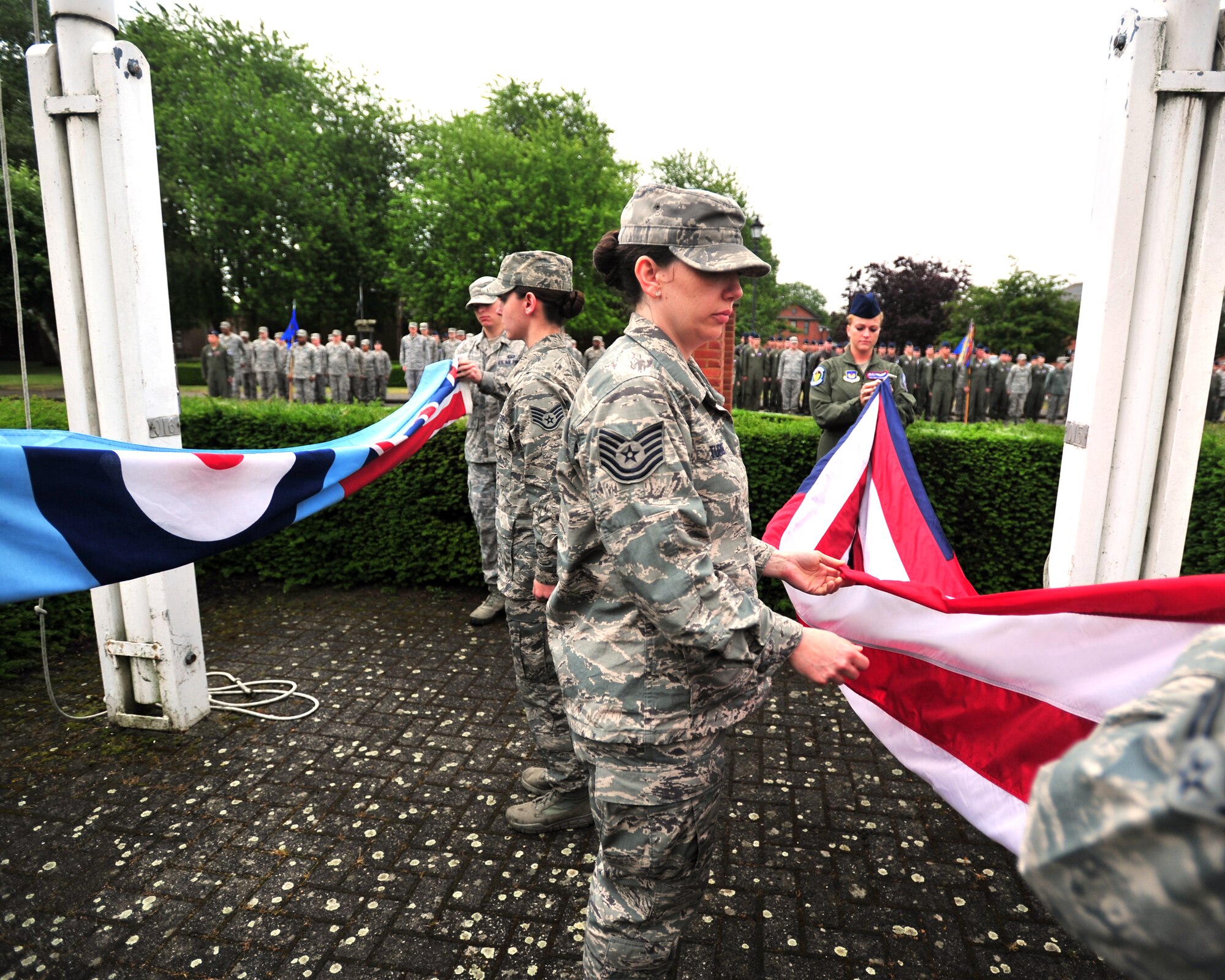 Tech. Sgt. Natalie Turner, Team Mildenhall flag detail team NCO in charge, helps team members fold the U.S. flag and Royal Air Force ensign during the monthly retreat ceremony June 28, 2013, on RAF Mildenhall, England. A retreat ceremony, in which the U.S. flag and Royal Air Force ensign are retired, takes place on the last Friday of every month. (U.S. Air Force photo/Master Sgt. Brian M. Boisvert/Released)