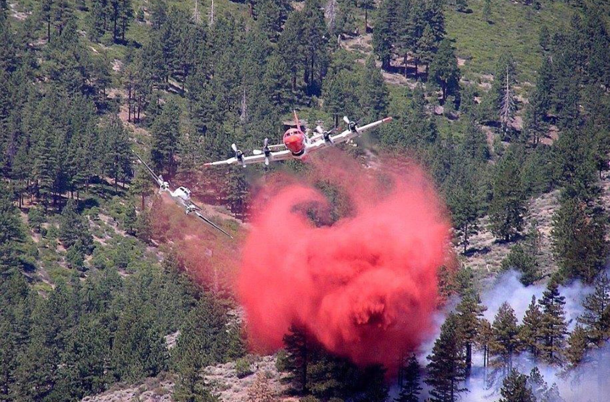 A small and maneuverable Beech King Air, like the one flown by Lt. Col. Paul Delmonte while on the job with the U.S. Forest Service, pulls away after leading a tanker to a retardant drop spot over a wildfire. During peak fire season, May to October, forest service lead plane pilots can assist in putting out as many as 60 fires. (Courtesy photo)