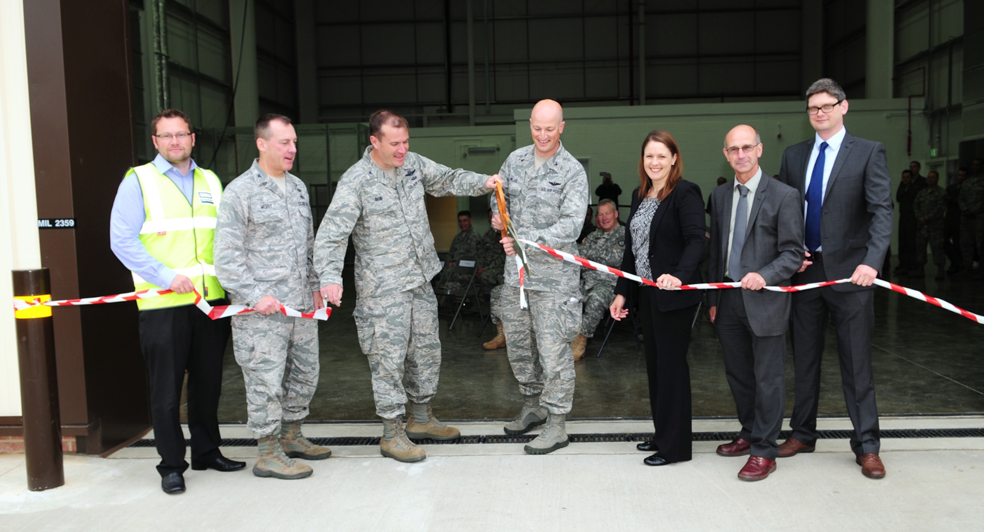 From left, Giles Perrin, Graham Construction project manager; Col. Daniel Merry, 100th Mission Support Group commander; Col. Kenneth T.  Bibb Jr., 100th Air Refueling Wing commander; Col. Christopher Ireland, 352nd Special Operations Group commander; Danielle Poyant, 352nd SOG civil engineer; Roger Martin, Defence Infrastructure Organization area manager; and Dominic Brown, Mott MacDonald Ltd., cut the ribbon at the ribbon-cutting ceremony for the CV-22 Osprey simulator facility June 21, 2013, on RAF Mildenhall, England. Ground-breaking for the simulator facility began in November 2012. (U.S. Air Force photo by Karen Abeyasekere/Released)