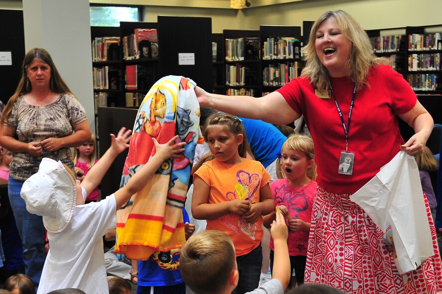 Kimberly Webb, 4th Force Support Squadron library director, hands out a summer reading program blanket as a raffle prize at the library at Seymour Johnson Air Force Base, N.C., June 25, 2013. More than 100 children, from newborn to the age of six, attended the summer travel safety-themed puppet show as a part of the library’s summer reading program. (U.S. Air Force photo by Senior Airman Aubrey White/Released)
