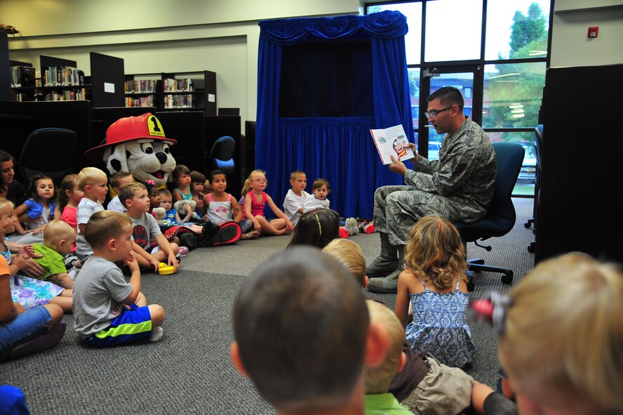 U.S. Air Force Tech. Sgt. Brandon Sanderson, 4th Civil Engineer Squadron NCO in charge of fire prevention, reads a story to children attending the library’s summer reading program at Seymour Johnson Air Force Base, N.C., June 25, 2013. This year’s summer reading program theme is “Have Book – Will Travel.” (U.S. Air Force photo by Senior Airman Aubrey White/Released)