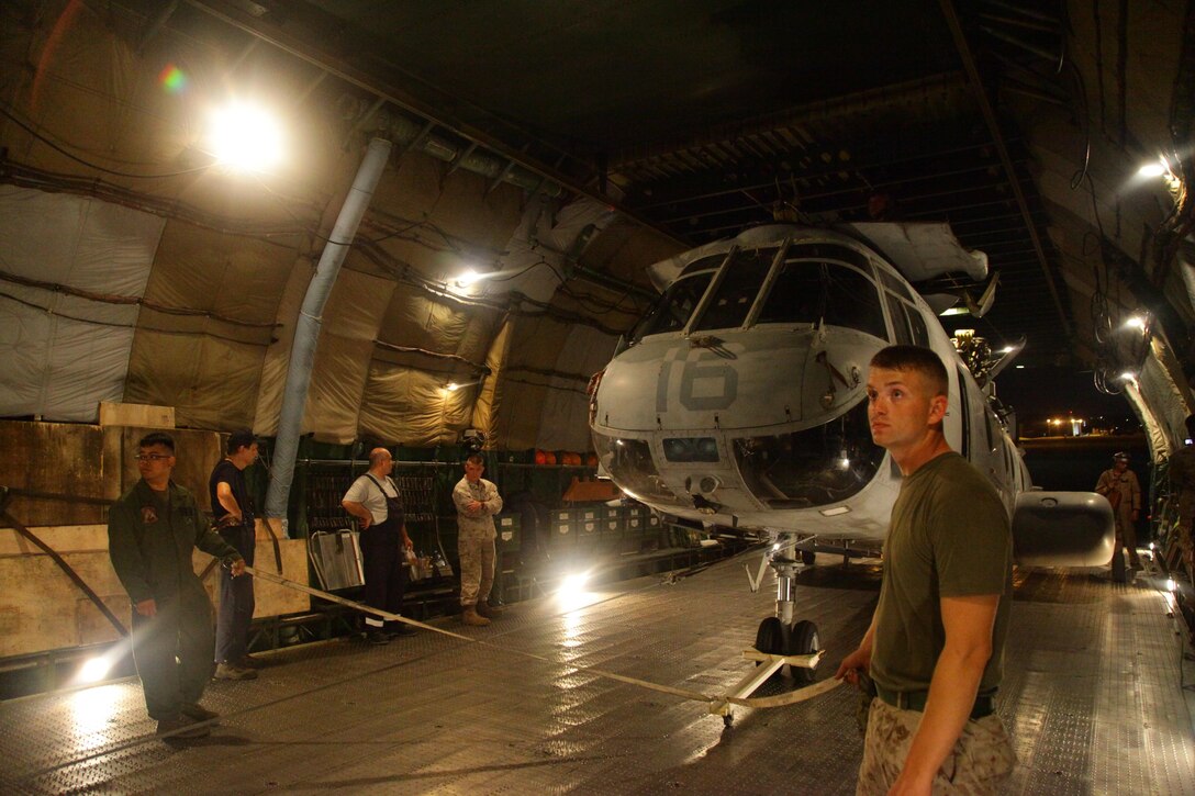 Sgt. Hieu V. Nguyen, left, and Cpl. Andrew T. Myatt guide a CH-46E Sea Knight helicopter into an An-124 cargo aircraft June 17 at Marine Corps Air Station Futenma. Myatt and Nguyen are CH-46 mechanics with the Marine Medium Helicopter Squadron 262, Marine Aircraft Group 36, 1st Marine Aircraft Wing, III Marine Expeditionary Force. The cargo aircraft and its crew are with a Russian Federation contractor. (U.S. Marine Corps photo by Lance Cpl. Natalie M. Rostran/Released)