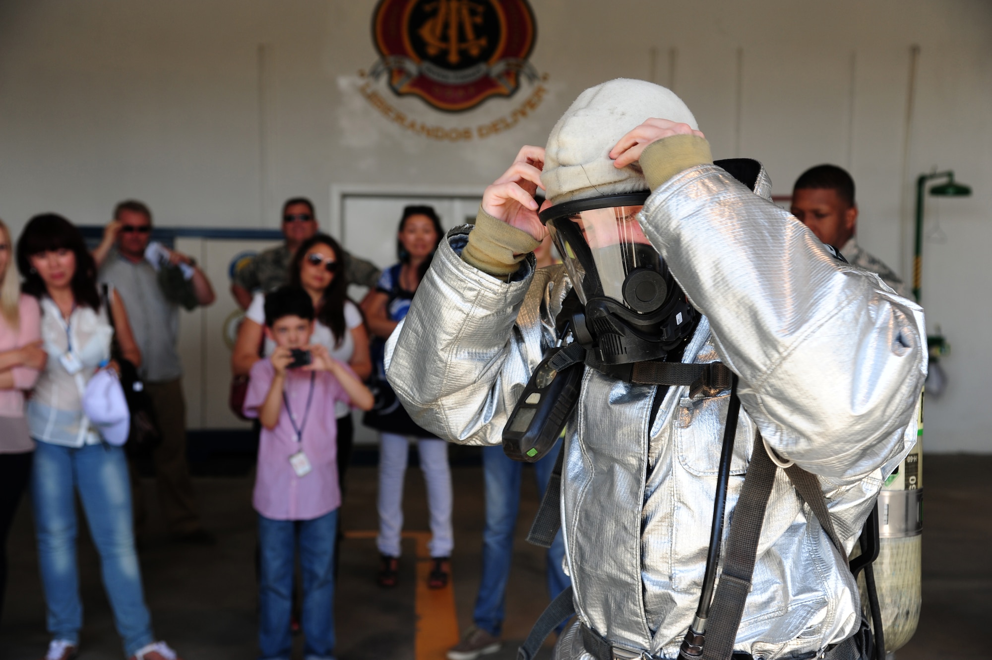 Airman 1st Class Brandon Ouellette, 376th Expeditionary Civil Engineer Squadron, firefighter, puts on his protective equipment for visitors during a tour of the fire department at Transit Center at Manas, Kyrgyzstan, June 25, 2013. Ouellette is deployed from Royal Air Force Lakenheath, United Kingdom and is a native of Dundee, Michigan. (U.S. Air Force photo/Staff Sgt. Krystie Martinez)