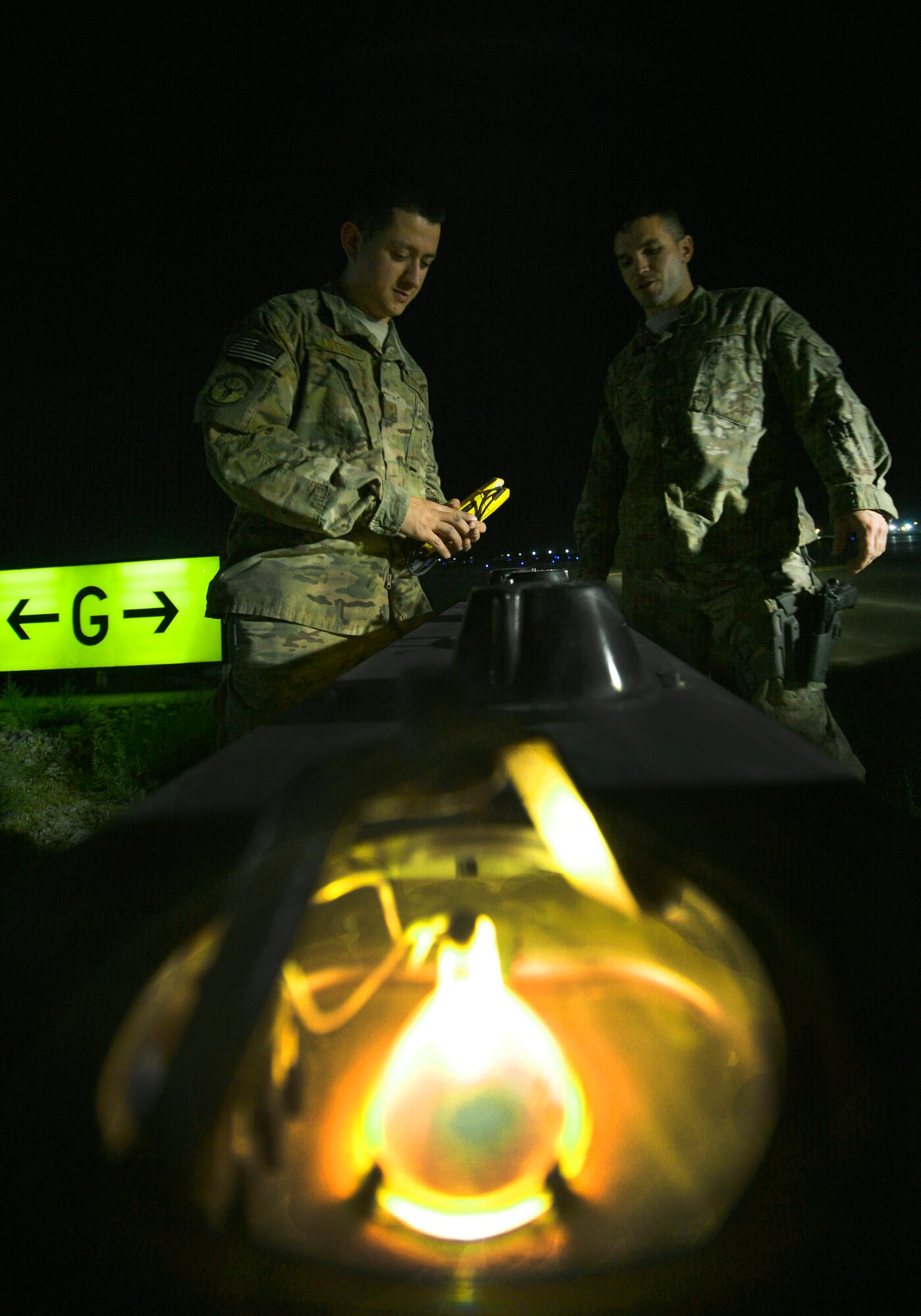 Tech. Sgt. Blake Moulden and Justin Lotero, prepare to replace a runway light bulb at Bagram Airfield, Afghanistan, June 6. They both are assigned to the 455th Expeditionary Civil Engineer Squadron electrical systems shop and are a part of a three-man airfield lighting crew in charge of maintaining more than one-thousand lights spanning over one-million square feet here. (U.S. Air Force photo/Staff Sgt. Stephenie Wade) 