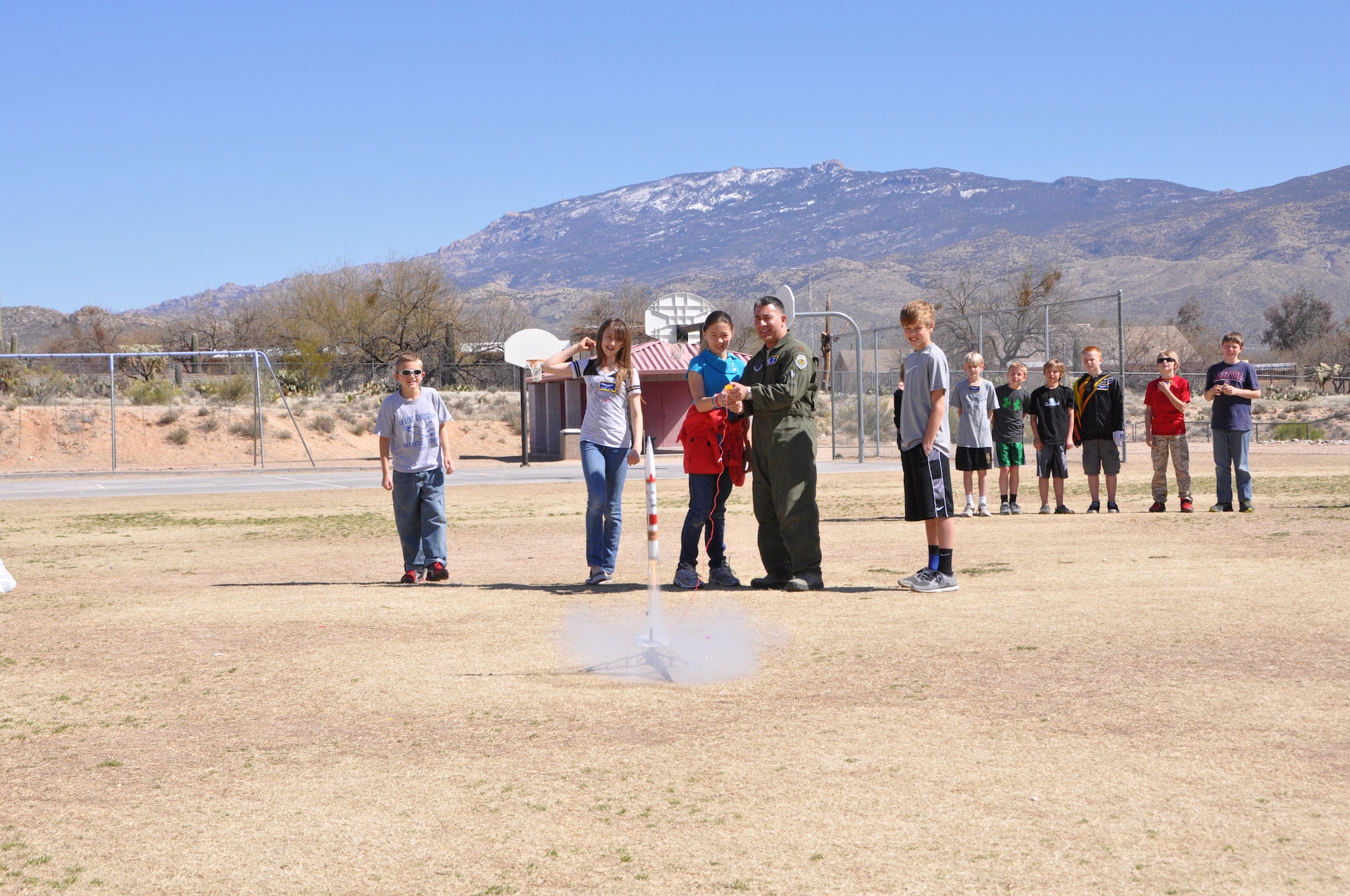Maj. Andre Benitez, 612th Air and Space Operations Center, shoots off a rocket during a demonstration at Tanque Verde Elementary School in Tucson, Ariz., March 1. Airmen from 12th Air Force (Air Forces Southern) gave 5th grade students a lesson on space operations (launch operations, weather support, launch control centers and the importance of launch observation and recovery) during their visit. (USAF photo by Lt. Col. Dan Jones/Released). 