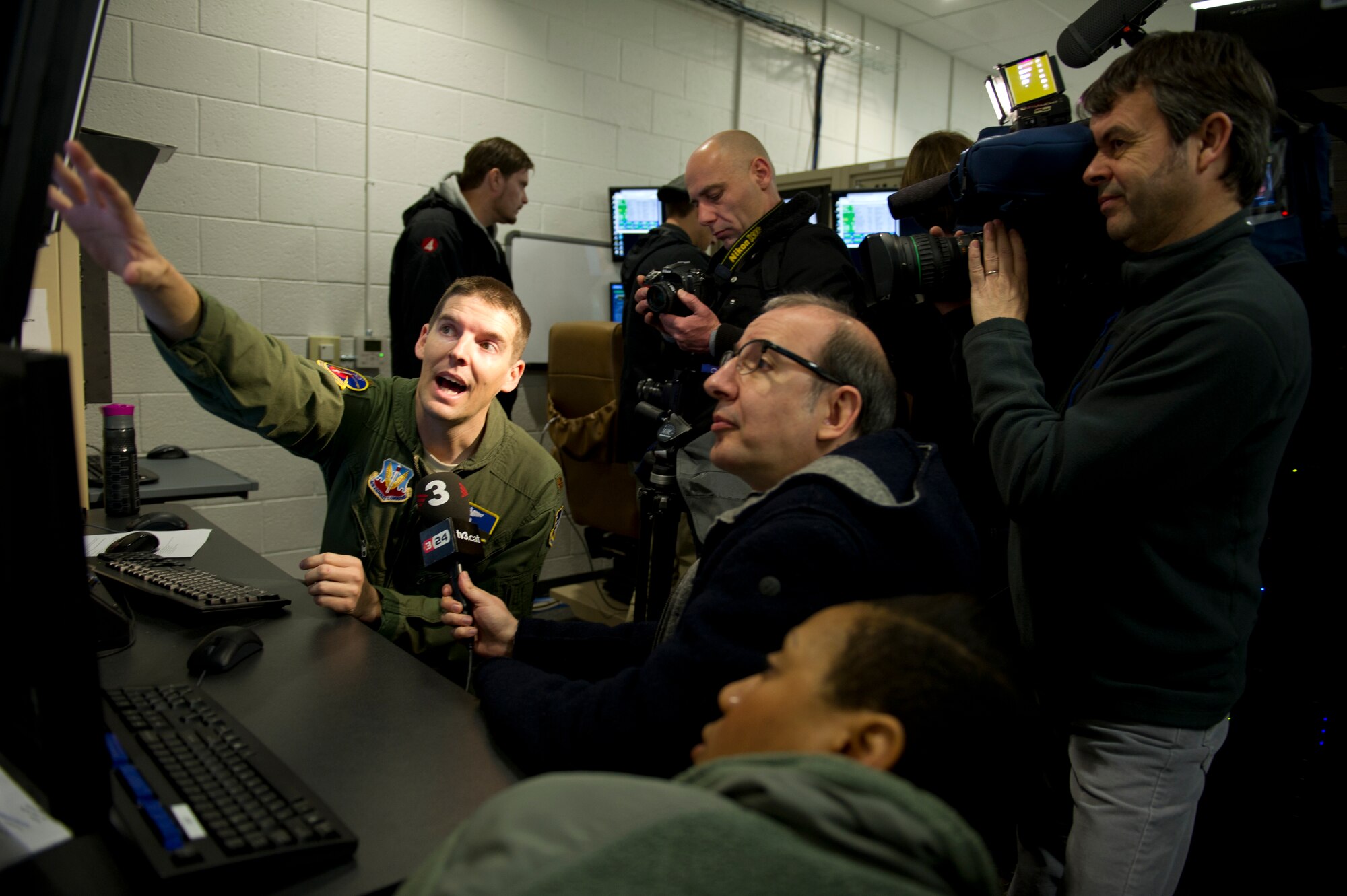 Major Dennis (last name omitted due to operational security concerns), 16th Training Squadron director of operations, explains to media a flying scenario from the MQ-1 Predator and MQ-9 Reaper simulators during a media day at Holloman Air Force Base, N.M., Feb. 28. The MQ-1 and MQ-9 are armed, multi-mission, medium-altitude, long endurance Remotely Piloted Aircraft that are employed in an armed reconnaissance role, collecting intelligence and providing direct strike capability. (U.S. Air Force photo by Senior Airman Kasey Close/Released)