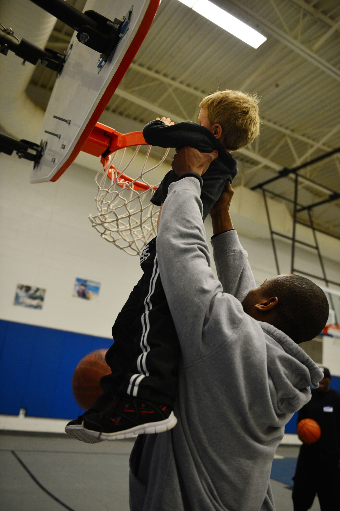 U.S. Air Force Staff Sgt. James Dexter, 27th Special Operations Civil Engineer Squadron, lifts a child up so he can dunk a basketball through the hoop at a youth basketball clinic held in the Youth Center at Cannon Air Force Base, N.M., Feb. 26, 2013. Cannon's men's varsity basketball team hosted a youth basketball clinic for children, ages 6-11, to teach them standard fundamentals of the game. (U.S. Air Force photo/Airman 1st Class Eboni Reece)