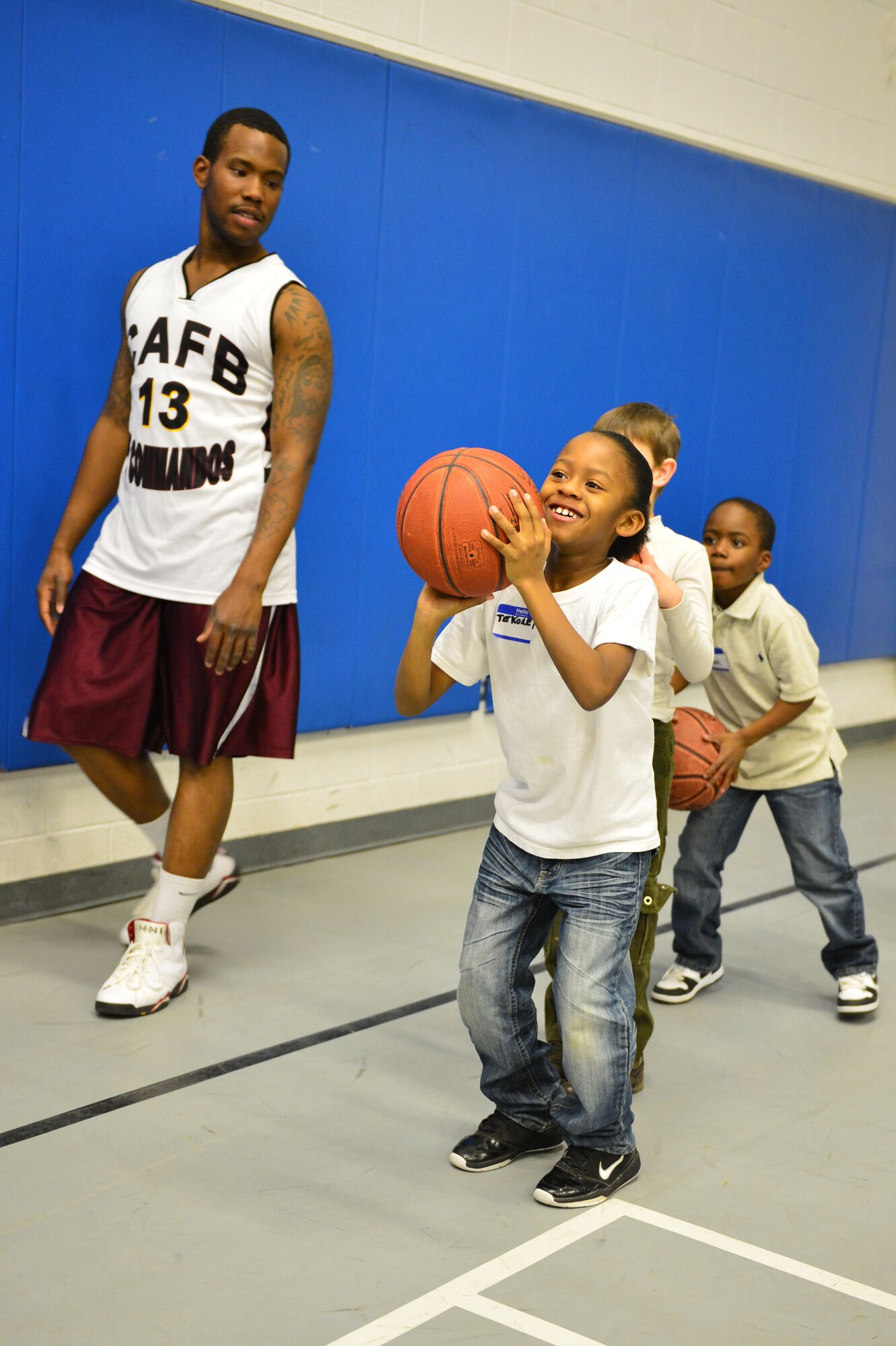U.S. Air Force Senior Airman Ronald Graham, 27th Special Operations Civil Engineer Squadron Heating Ventilation and Air Conditioning technician, watches as a child participates in a shooting drill during a youth basketball clinic held in the Youth Center at Cannon Air Force Base, N.M., Feb. 26, 2013. Cannon's men's varsity basketball team hosted a youth basketball clinic for children, ages 6-11, to teach them standard fundamentals of the game. (U.S. Air Force photo/Airman 1st Class Eboni Reece)