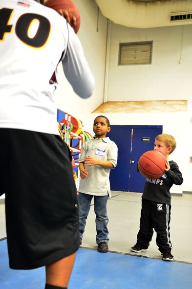 Children watch as Airman 1st Class Terrence Jackson, 27th Special Operations Comptroller Squadron finance customer service technician, teaches proper shooting technique during a youth basketball clinic held in the Youth Center at Cannon Air Force Base, N.M., Feb. 26, 2013. Cannon's men's varsity basketball team hosted a youth basketball clinic for children, ages 6-11, to teach them standard fundamentals of the game. (U.S. Air Force photo/Airman 1st Class Eboni Reece)