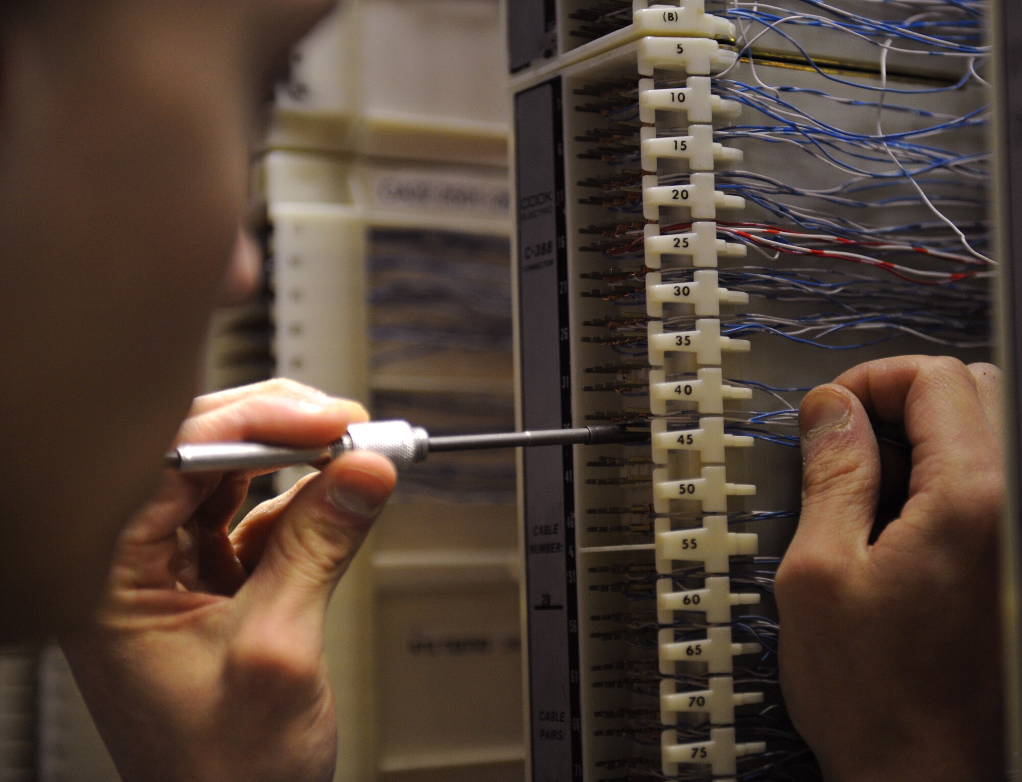 Airman 1st Class Jesse Christmas, 2nd Communications Squadron cyber transport systems technician, connects a wire to a phone port on Barksdale Air Force Base, La., March 1. Airmen from the 2 CS were running cables to other buildings on base to ensure those buildings have telephone access. (U.S. Air Force photo/Airman 1st Class Benjamin Gonsier)
