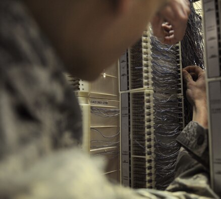 Airman 1st Class Jesse Christmas, 2nd Communications Squadron cyber transport systems technician, maneuvers a wire through a small passageway to connect to a phone line on Barksdale Air Force Base, La., March 1. Airmen from the 2 CS cyber transport systems section provide voice and data network support for the whole base. (U.S. Air Force photo/Airman 1st Class Benjamin Gonsier)  