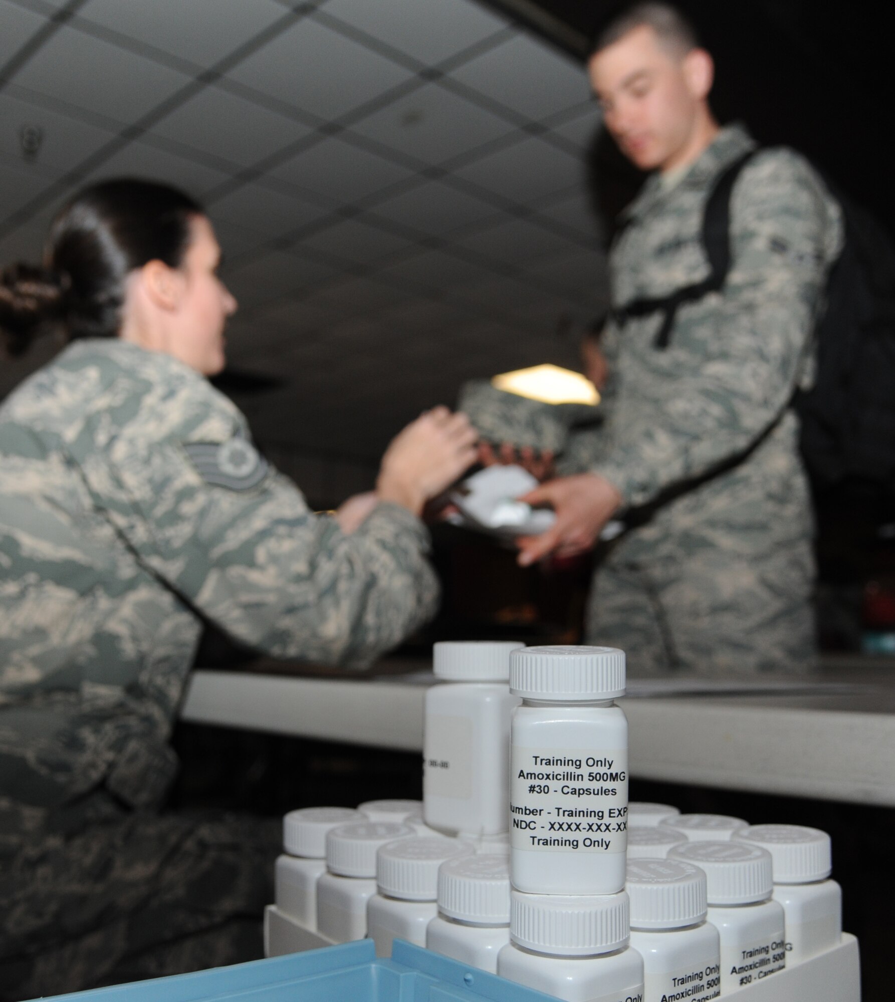 Tech. Sgt. Adrienne Iglesias, 81st Diagnostics and Therapeutics Squadron, provides “medication” to Airman 1st Class Bobby Greene, 336th Training Squadron, during a disease containment plan and point of dispensing exercise Feb. 28, 2013, near the Vandenburg Community Center, Keesler Air Force Base, Miss.  The scenario included a series of biological attacks in which numerous Keesler personnel became infected and the medical group had to distribute large quantities of medicine to efficiently minimize risk. (U.S. Air Force photo by Kemberly Groue)