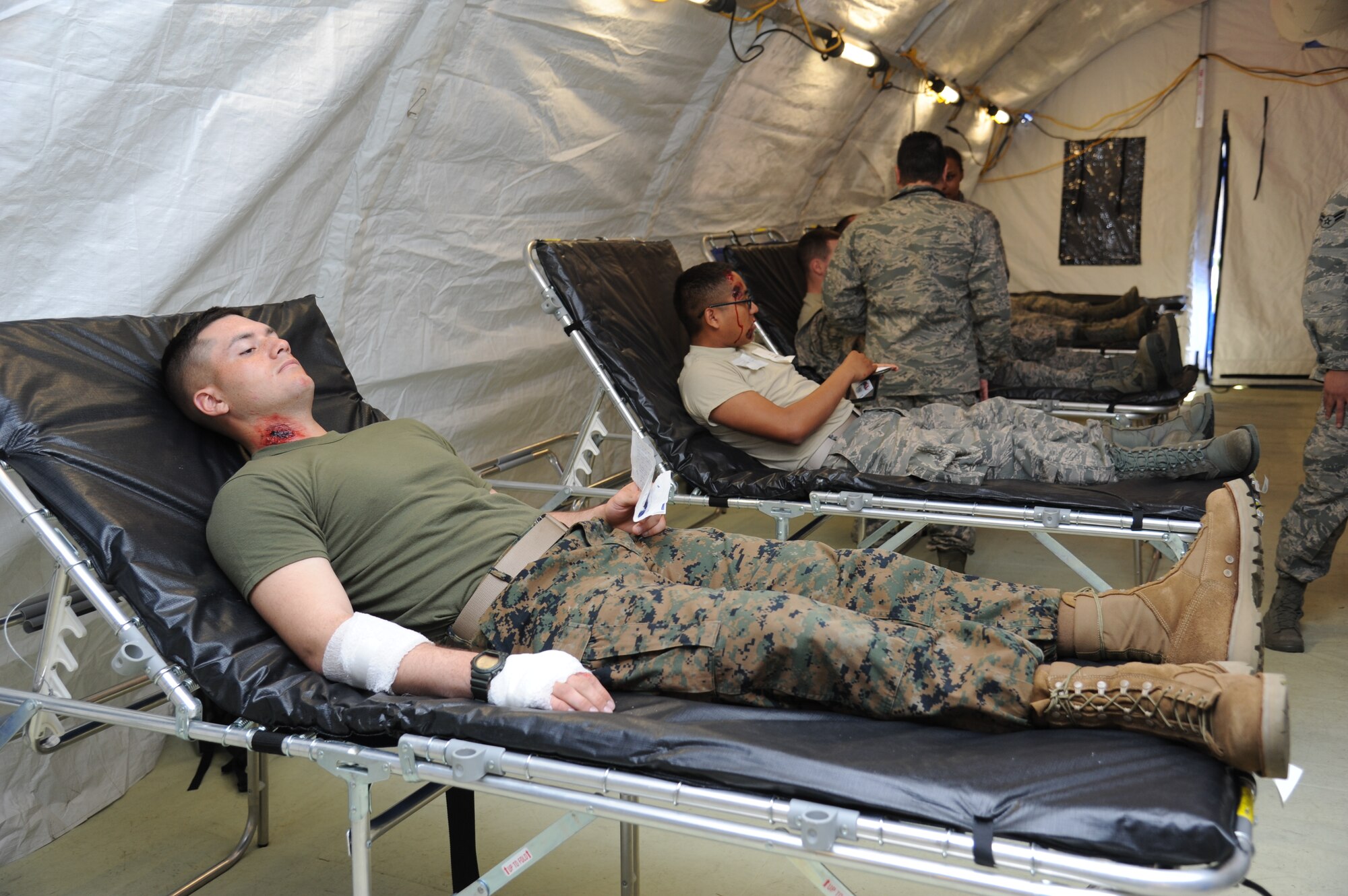 Marine Pvt. Jason Sexton, Keesler Marine Detachment, and Airman Basic Jose Brojas-Diaz, 336th Training Squadron, await further medical treatment inside the temporary medical facility during a disease containment plan and point of dispensing exercise Feb. 28, 2013, near the Vandenburg Community Center, Keesler Air Force Base, Miss.  The scenario included a series of biological attacks in which numerous Keesler personnel became infected and the medical group had to distribute large quantities of medicine to efficiently minimize risk. (U.S. Air Force photo by Kemberly Groue)