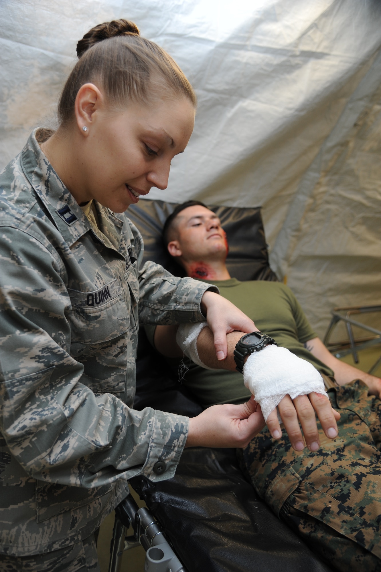 Capt. Karen Quinn, 81st Medical Operations Squadron, wraps a bandage on the hand of Marine Pvt. Jason Sexton, Keesler Marine Detachment, inside the temporary medical facility during a disease containment plan and point of dispensing exercise Feb. 28, 2013, near the Vandenburg Community Center, Keesler Air Force Base, Miss.  The scenario included a series of biological attacks in which numerous Keesler personnel became infected and the medical group had to distribute large quantities of medicine to efficiently minimize risk. (U.S. Air Force photo by Kemberly Groue)